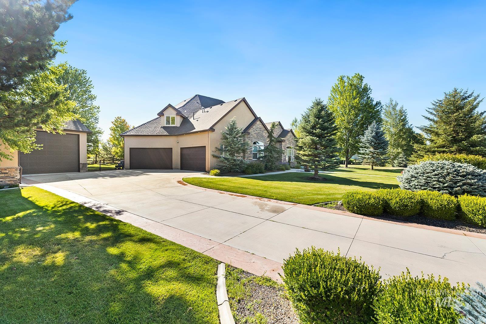 French country home with stone siding, a garage, a front yard, stucco siding, and driveway