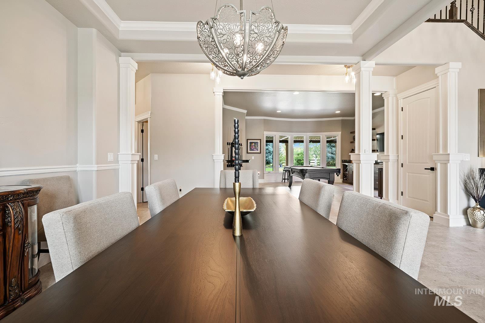 Dining area with crown molding, decorative columns, and a tray ceiling