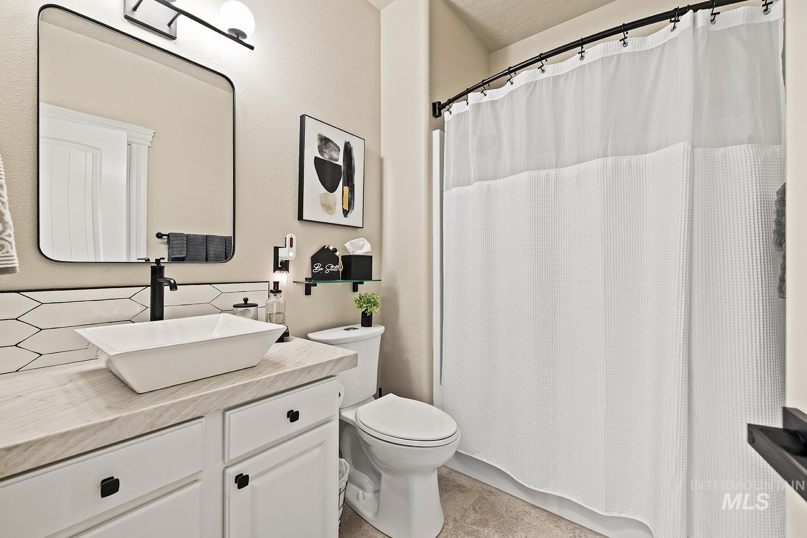 Bathroom featuring vanity, a shower with shower curtain, and backsplash