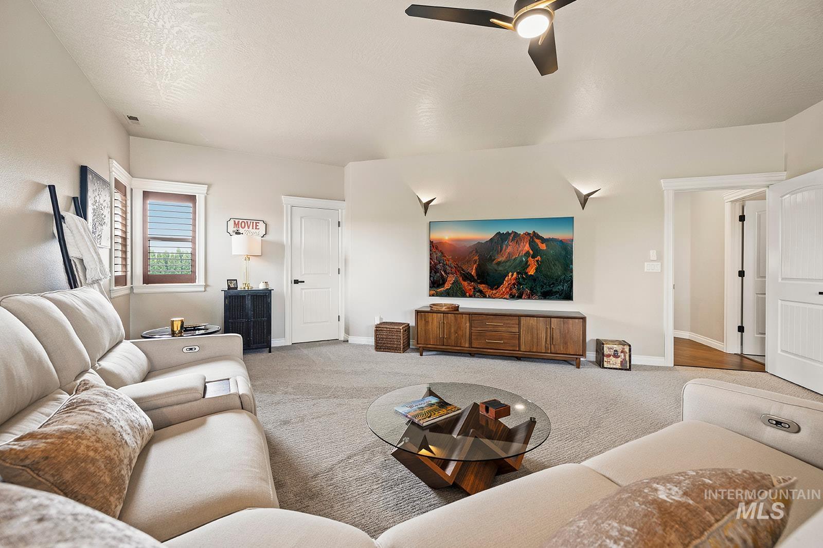 Carpeted living area with a textured ceiling and a ceiling fan