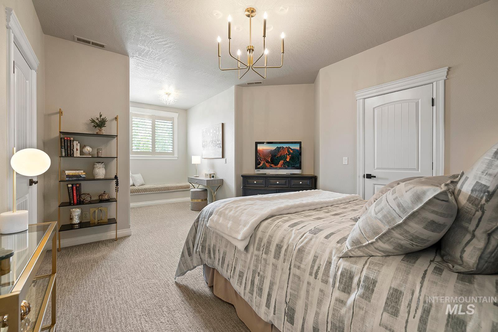 Bedroom featuring carpet flooring, a textured ceiling, and a chandelier