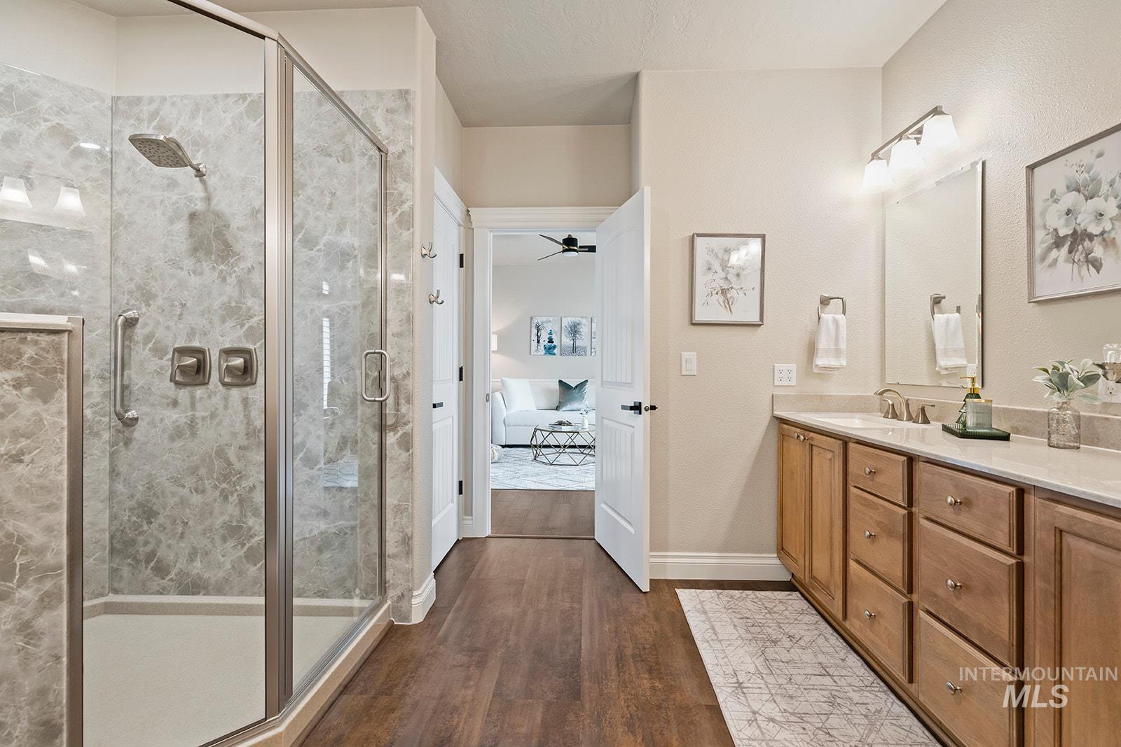 Ensuite bathroom featuring dark wood-type flooring, double vanity, a stall shower, and ceiling fan