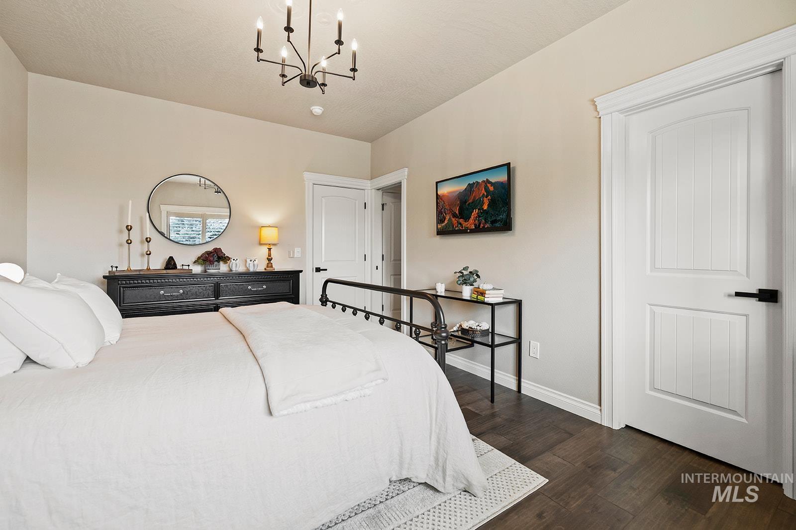 Bedroom with dark wood-style floors, a chandelier, and a textured ceiling