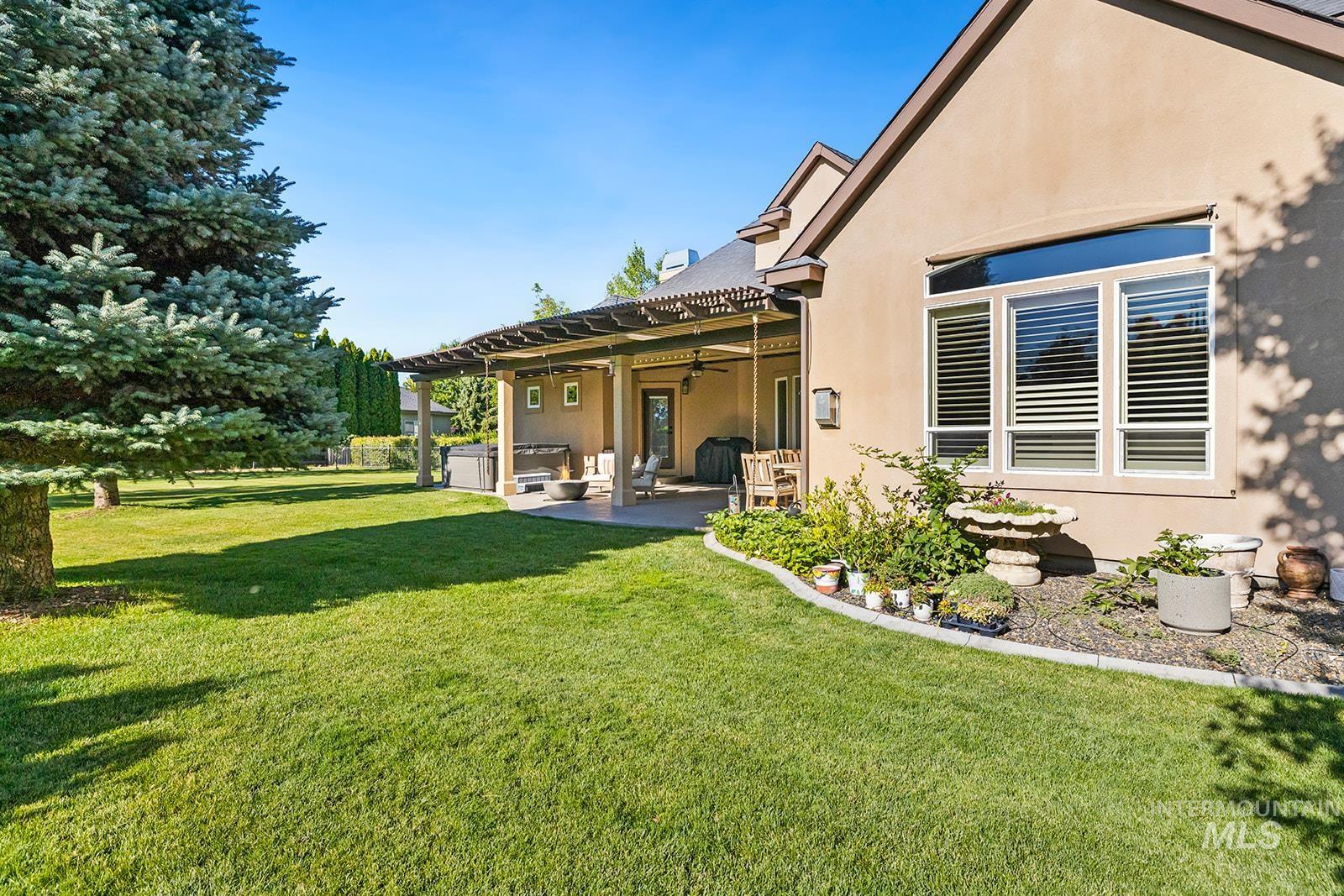 View of grassy yard featuring a hot tub, a patio, and ceiling fan
