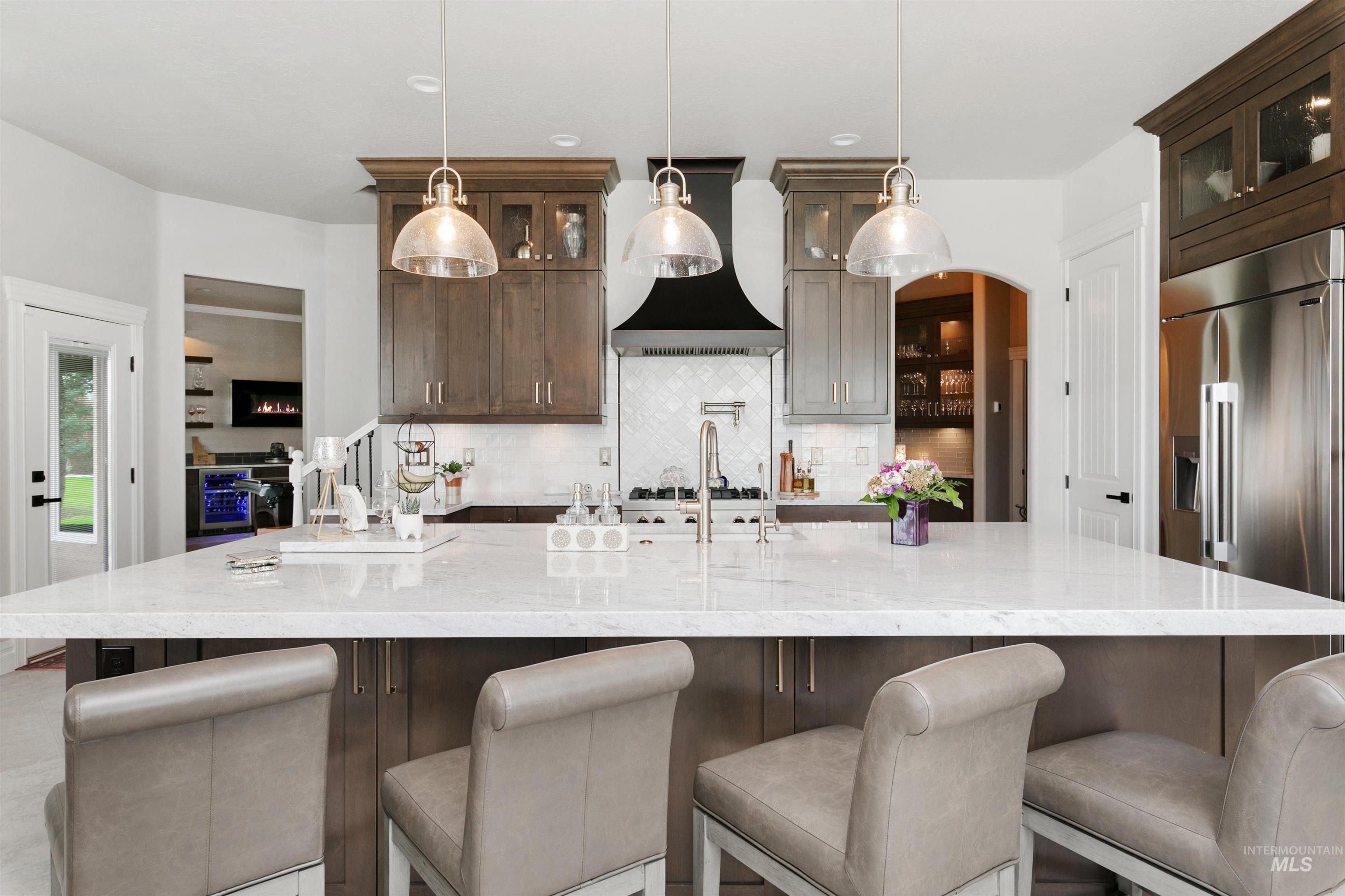Kitchen featuring dark brown cabinets, glass insert cabinets, light stone countertops, and recessed lighting
