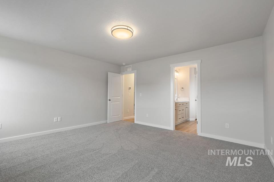 Unfurnished bedroom with light colored carpet and connected bathroom