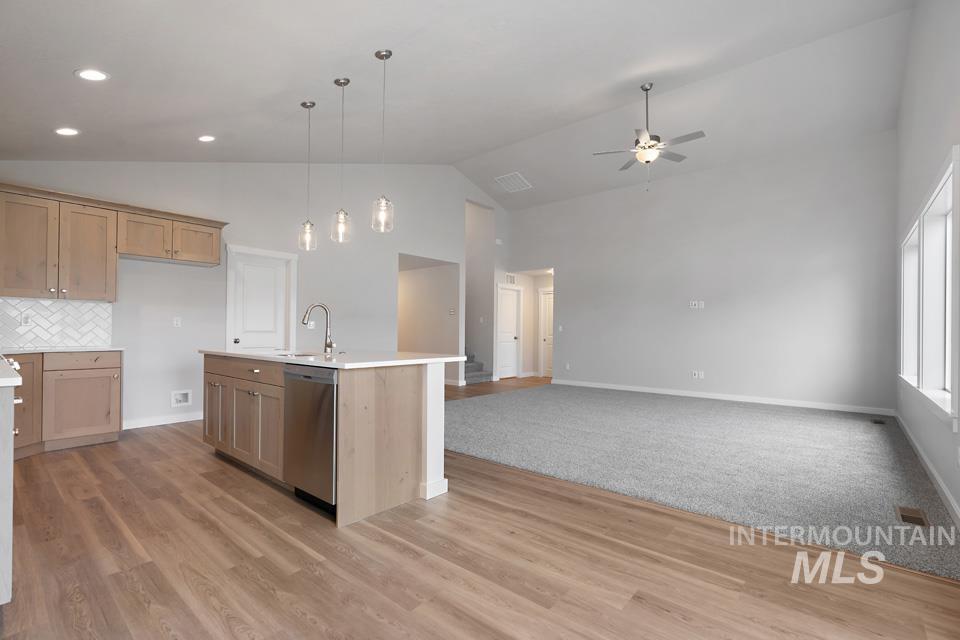 Kitchen featuring dishwasher, ceiling fan, high vaulted ceiling, light countertops, and open floor plan