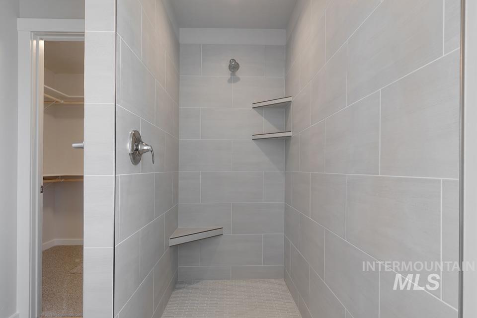 Bathroom with a tile shower and a walk in closet