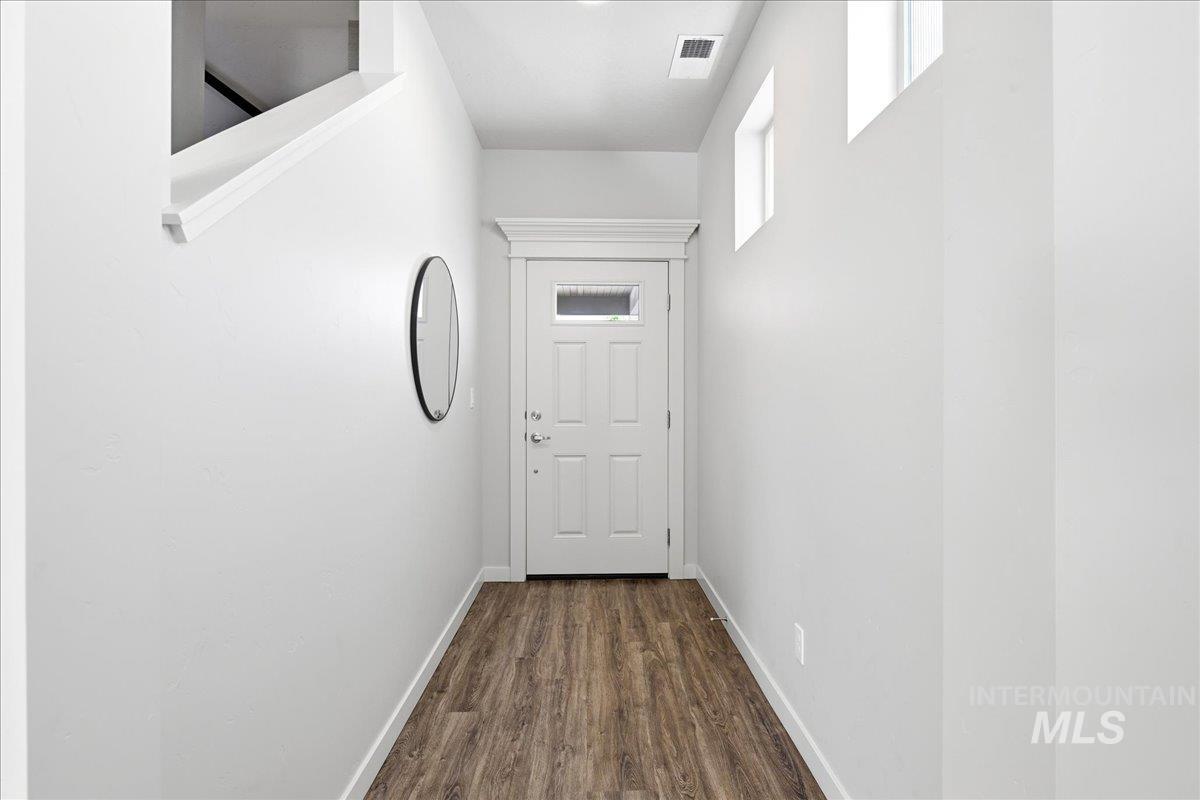 Entryway featuring wood-finish flooring, a white paneled door with an upper window, and two high wall windows