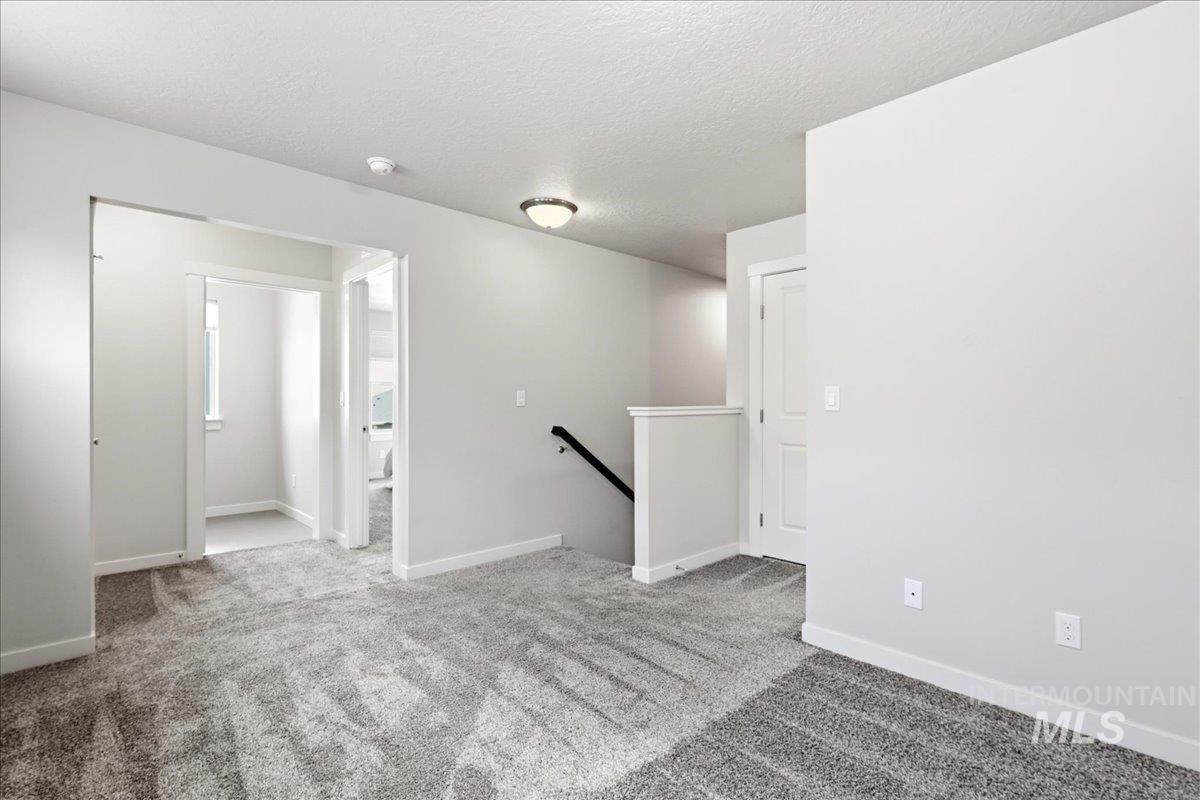 Upper level landing featuring light gray walls, gray speckled carpeting, and white trim