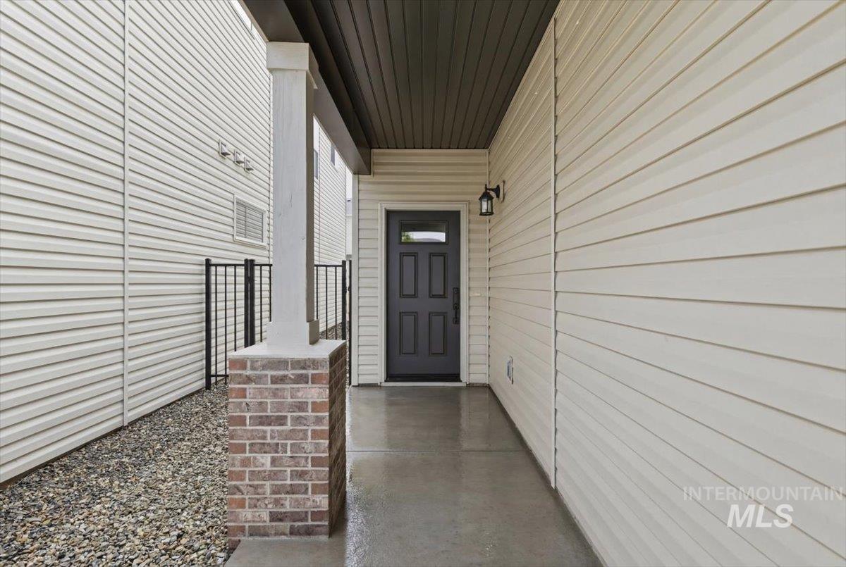 Covered entry featuring a dark-paneled door with a decorative glass insert, a black wall-mounted lantern, and light-colored siding