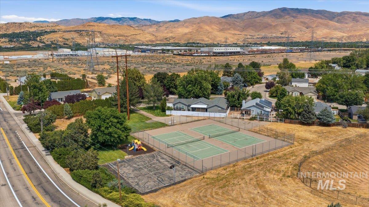 Four outdoor tennis courts with fencing, a dedicated playground area, and a paved court surface