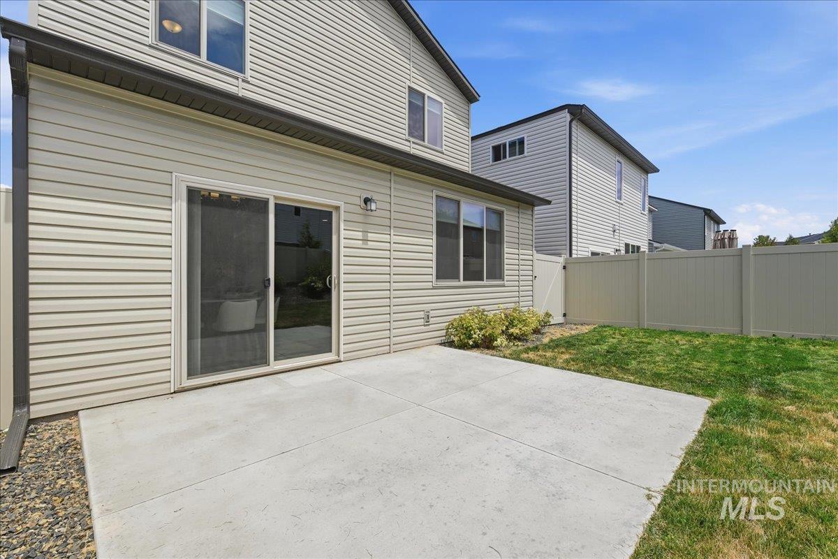 Rear exterior featuring a sliding glass door, concrete patio, and fenced yard