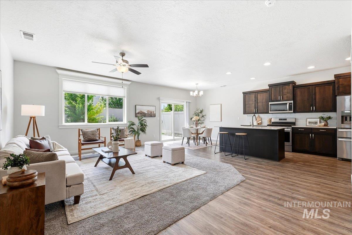 Open-concept living area with wood-finish flooring extending into the kitchen and dining area