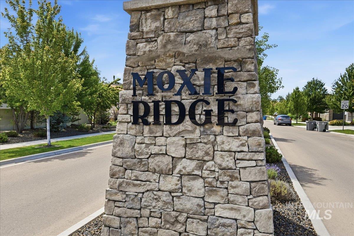 Stone pillar entrance featuring "Moxie Ridge" lettering, flanked by paved roadways and landscaped grounds