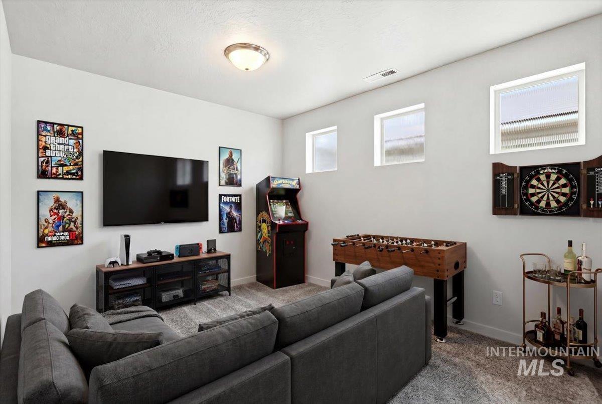 Flexible living space featuring light gray walls, an overhead ceiling light fixture, and gray textured carpeting
