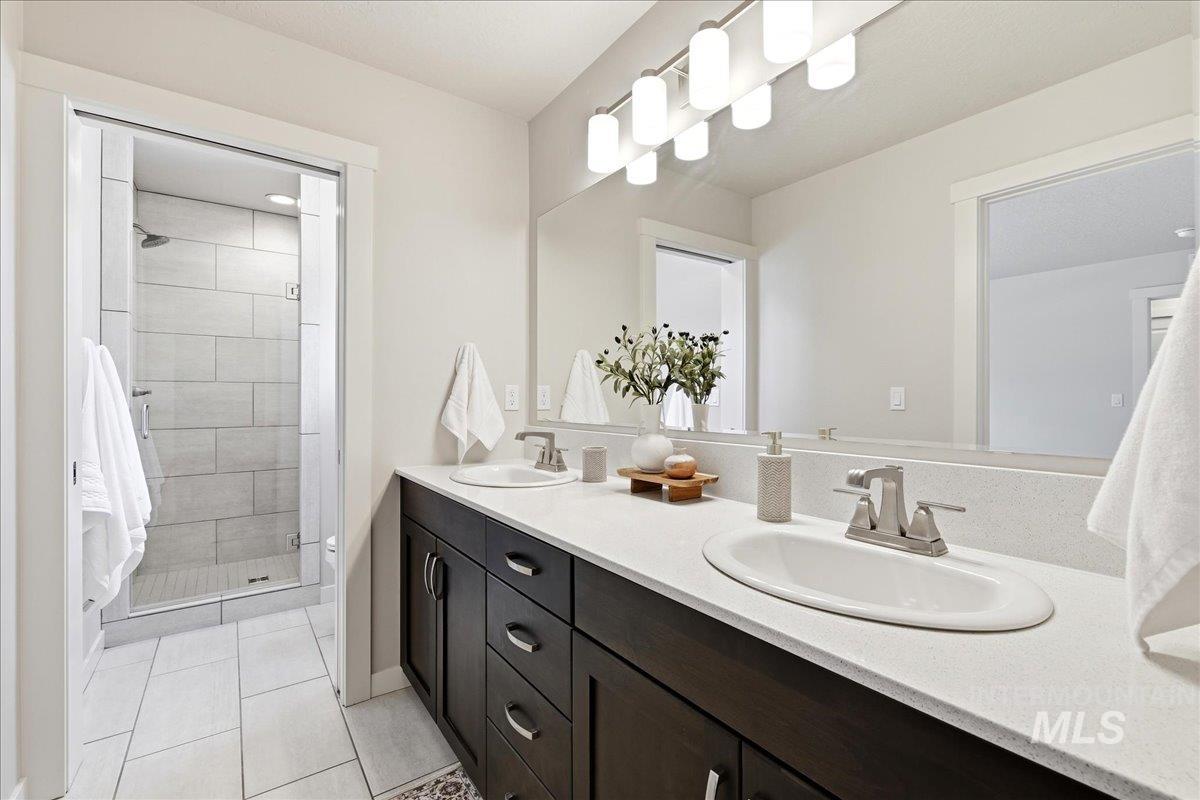 Bathroom featuring a dual-sink vanity with dark wood-finish cabinetry, light-toned countertop, and undermount sinks