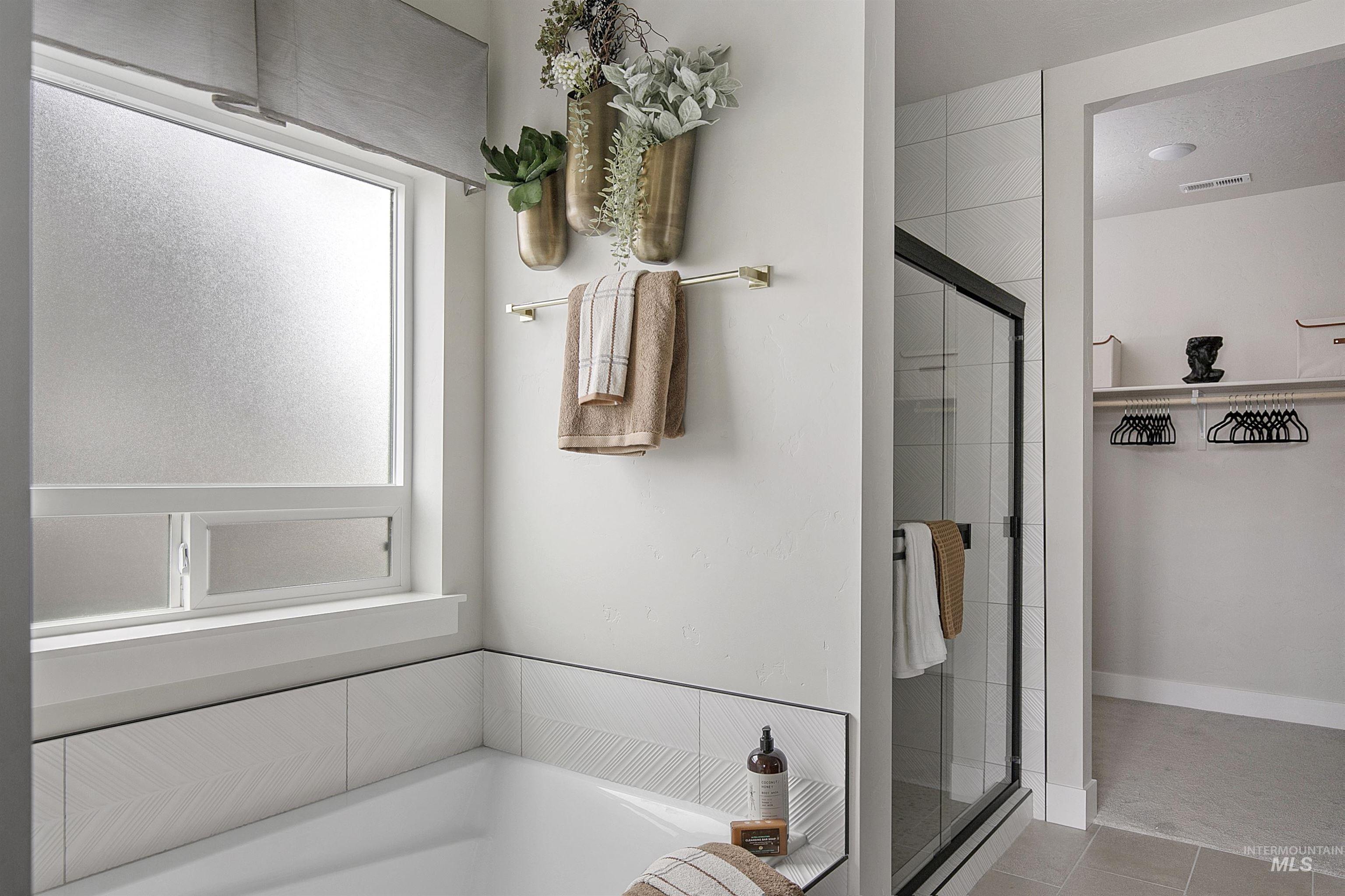 Bathroom featuring a shower stall, a bath, and tile patterned flooring