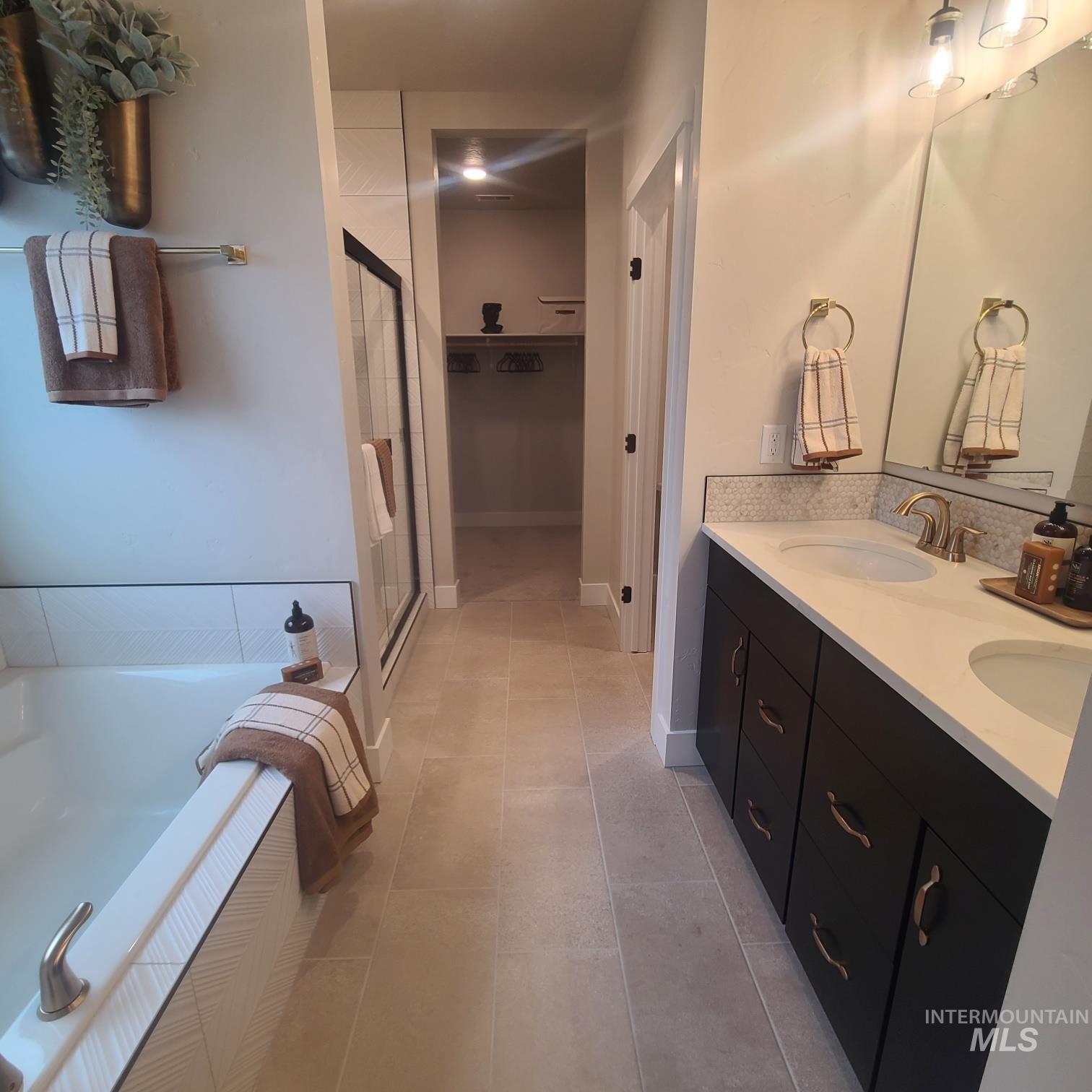 Full bathroom featuring a bath, a stall shower, double vanity, and light tile patterned flooring