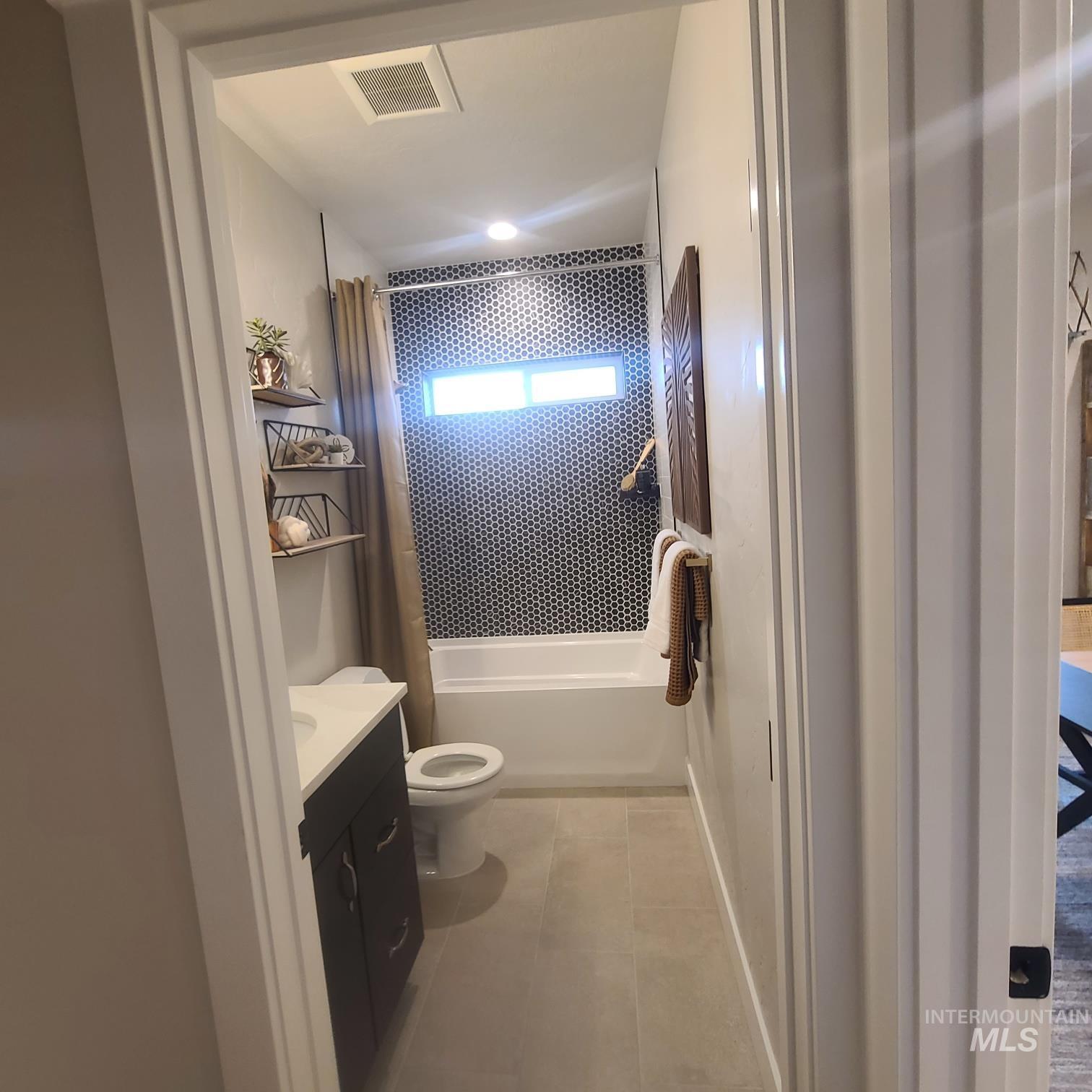Full bathroom with vanity, shower / bath combination with curtain, and light tile patterned floors