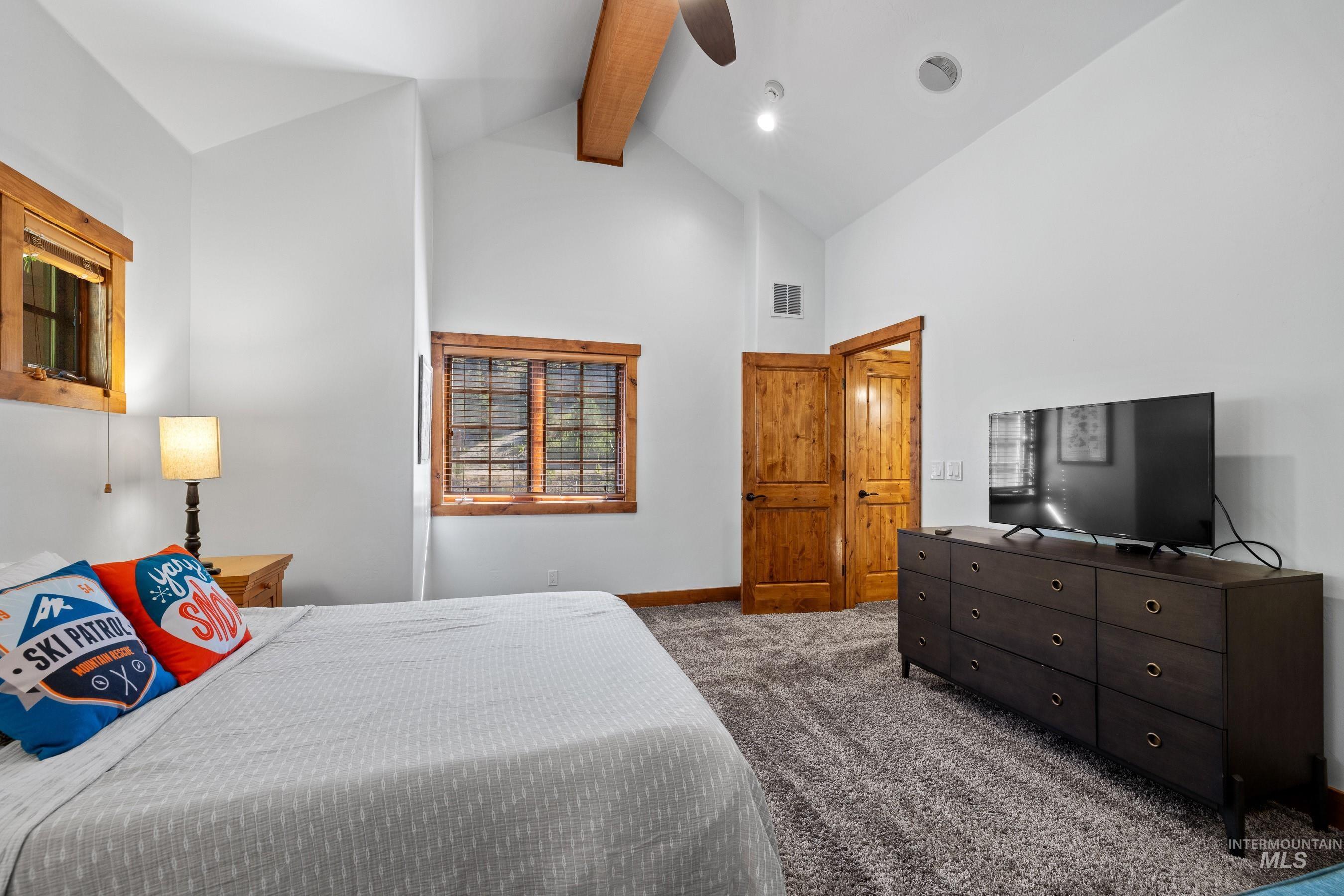 Carpeted bedroom featuring beamed ceiling, high vaulted ceiling, and a ceiling fan