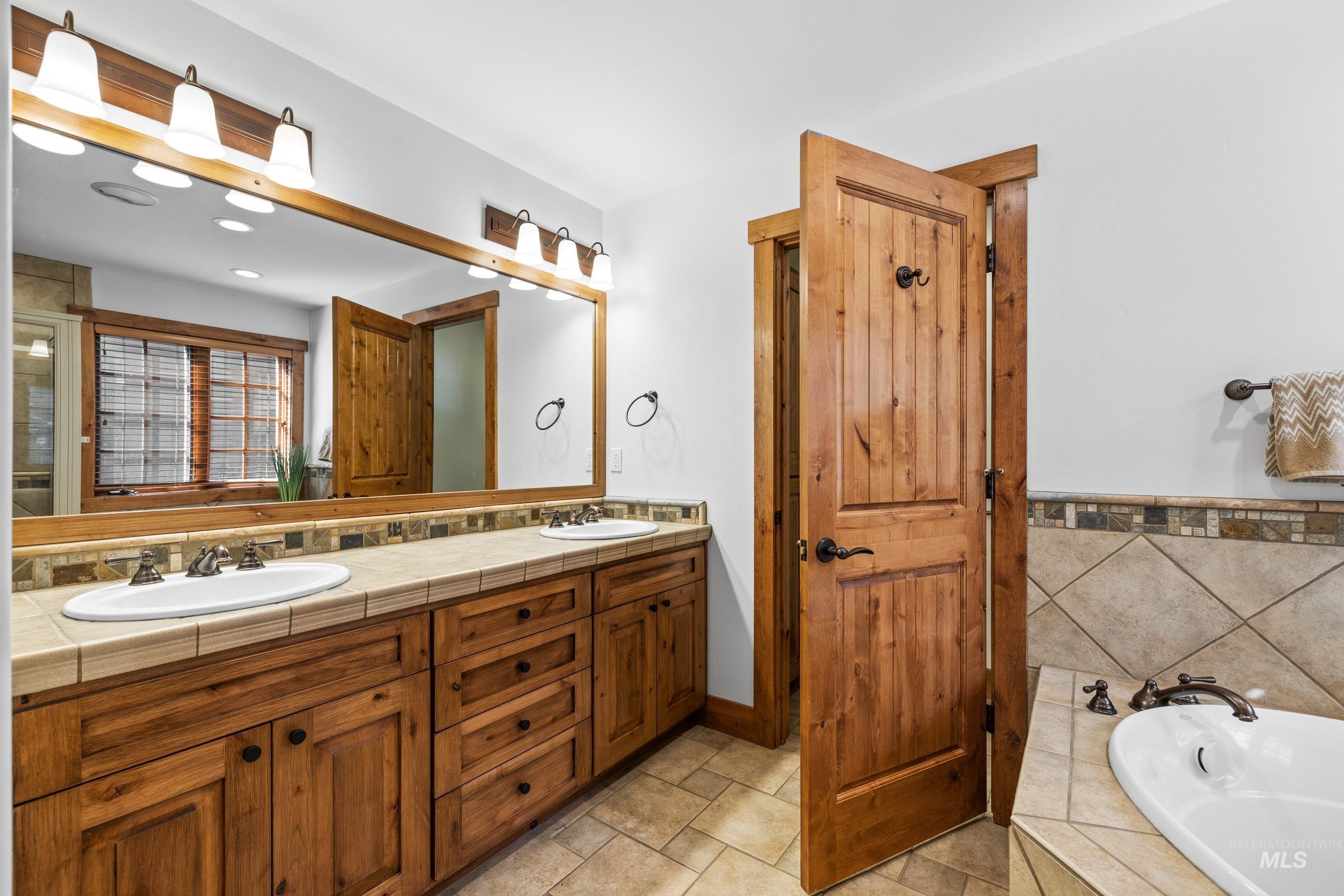 Full bath with double vanity, a bath, and recessed lighting