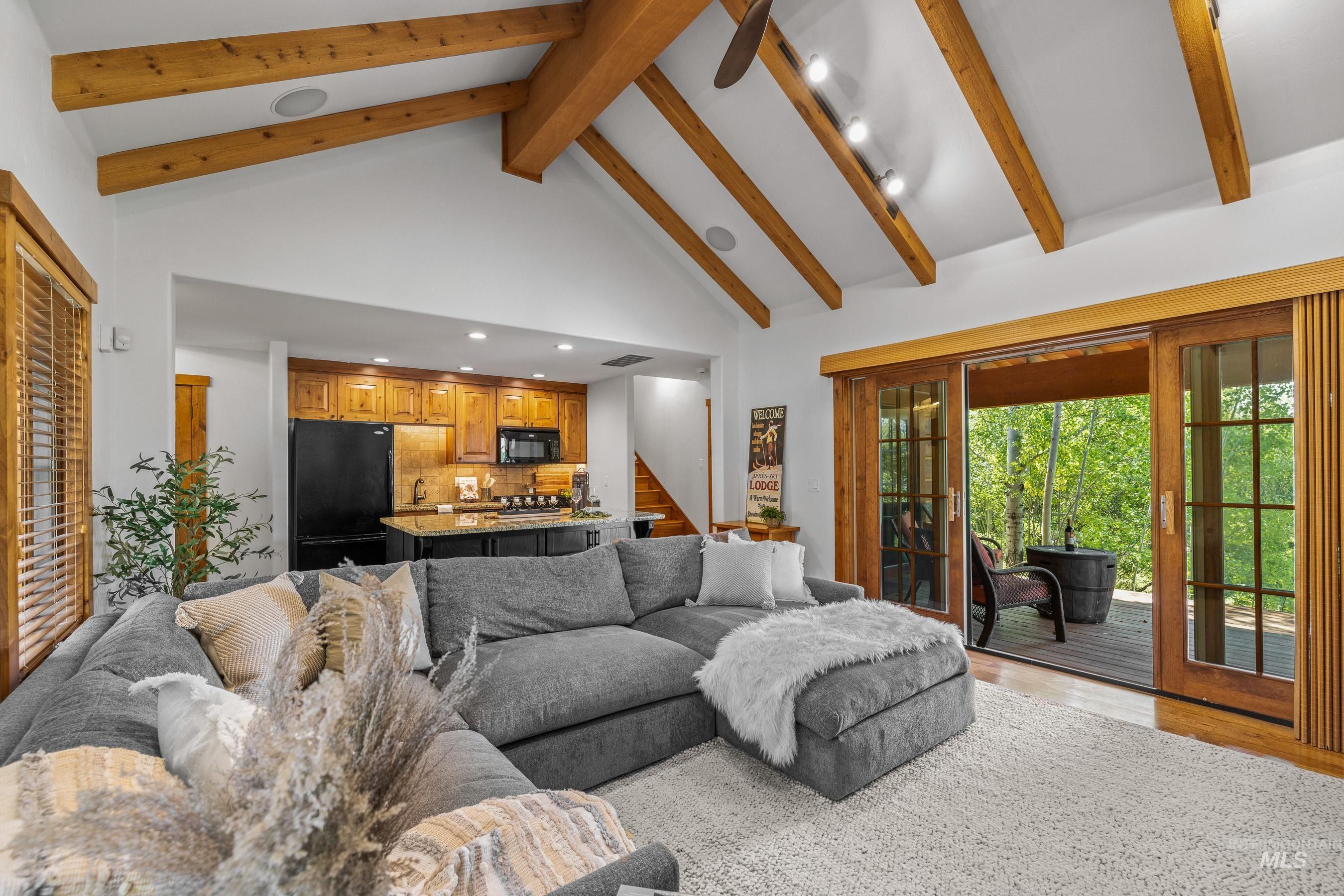 Living area featuring beamed ceiling, high vaulted ceiling, stairway, and wood finished floors