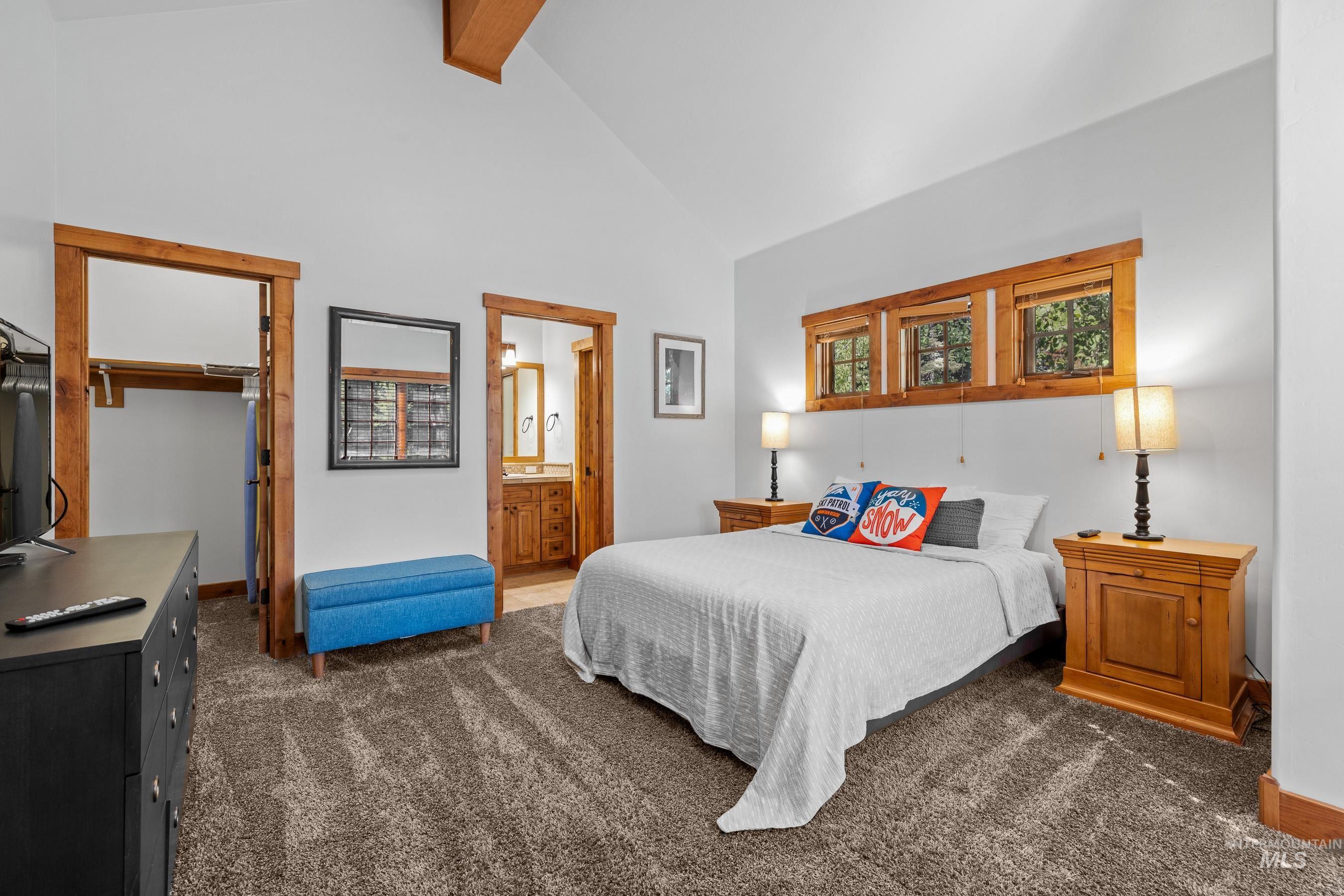 Bedroom featuring a walk in closet, high vaulted ceiling, carpet, beam ceiling, and connected bathroom