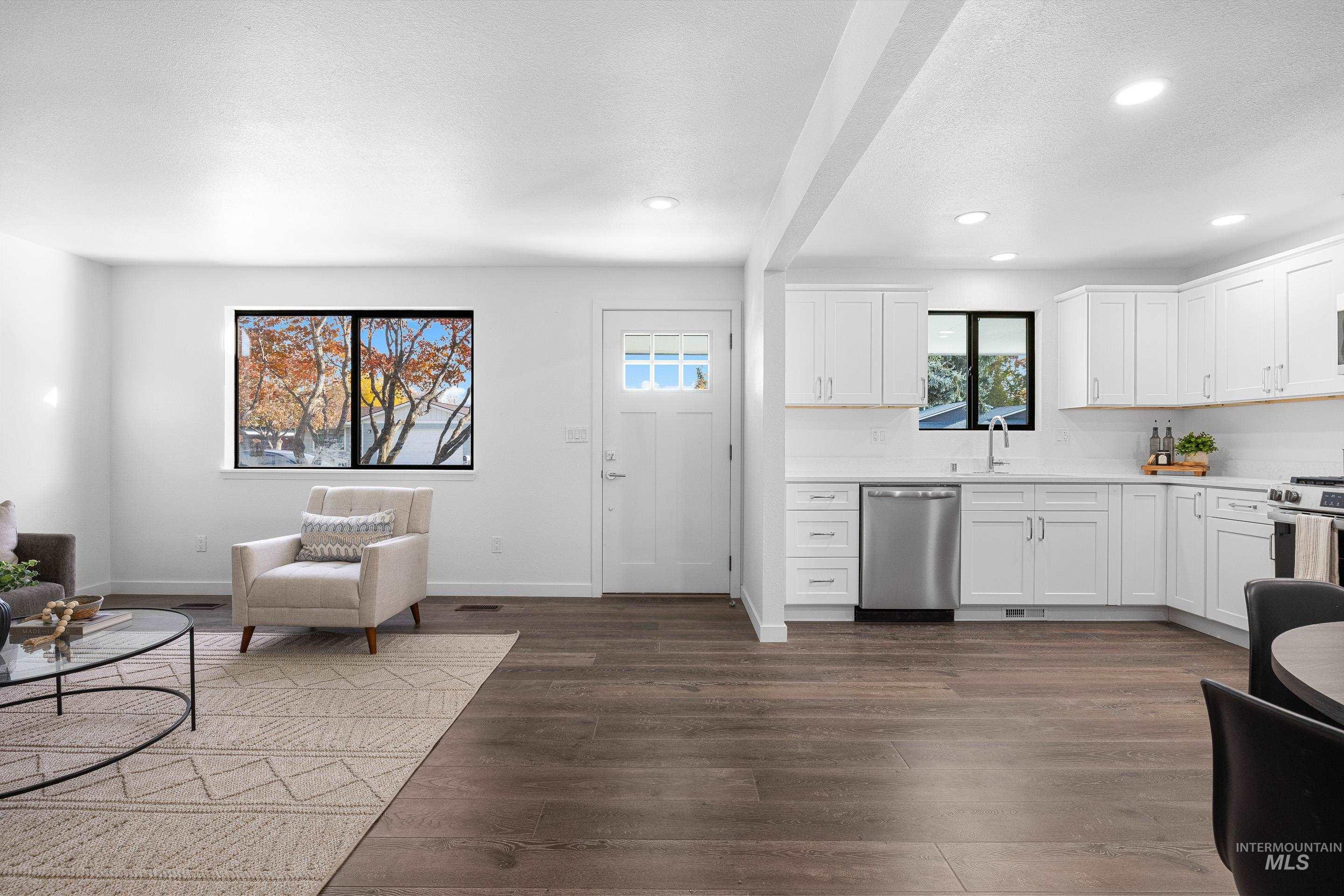 Kitchen with white cabinets, appliances with stainless steel finishes, dark wood-style flooring, recessed lighting, and a textured ceiling