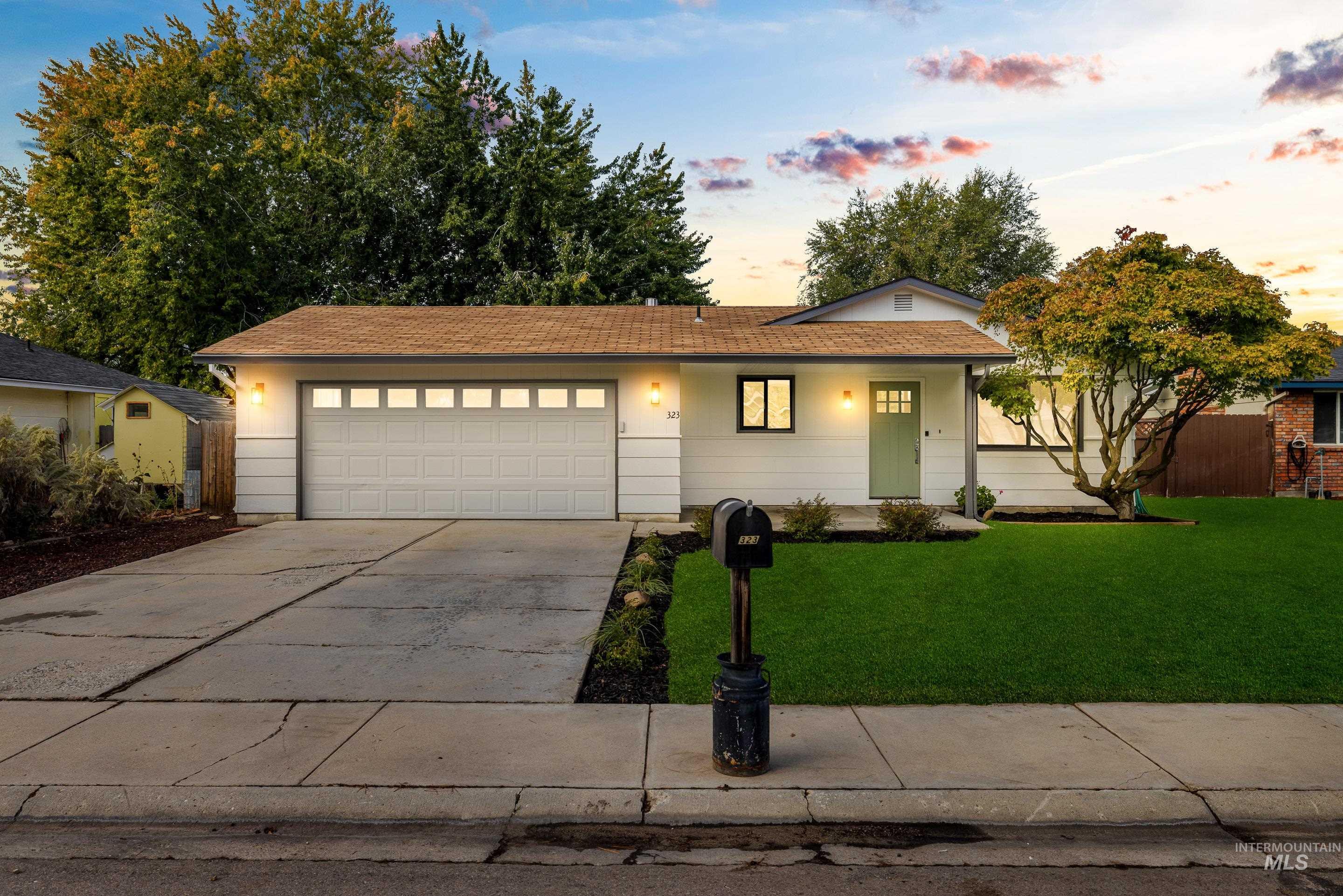 Ranch-style home featuring a front lawn, concrete driveway, and an attached garage