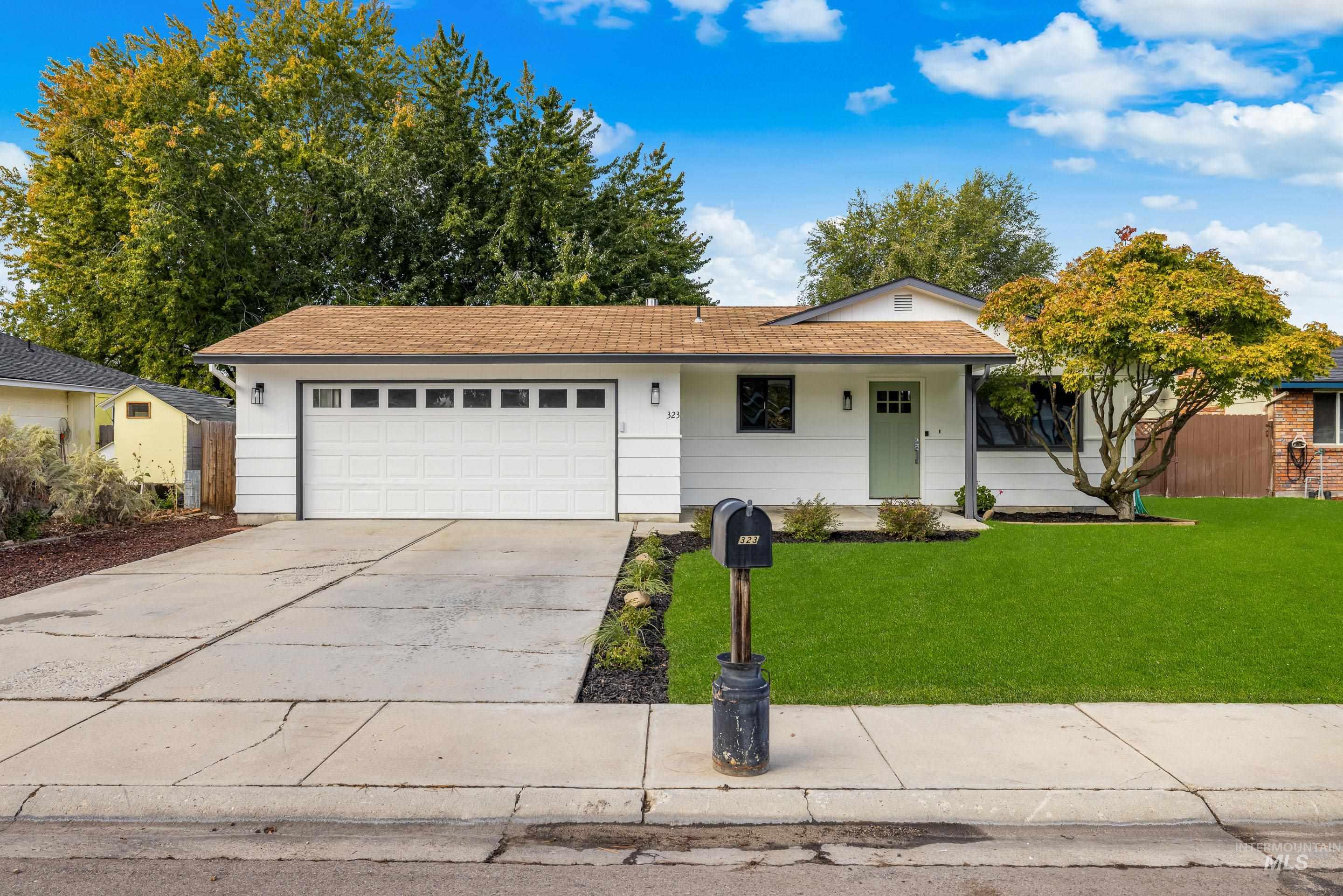 Ranch-style house with a front yard, concrete driveway, a garage, and a shingled roof