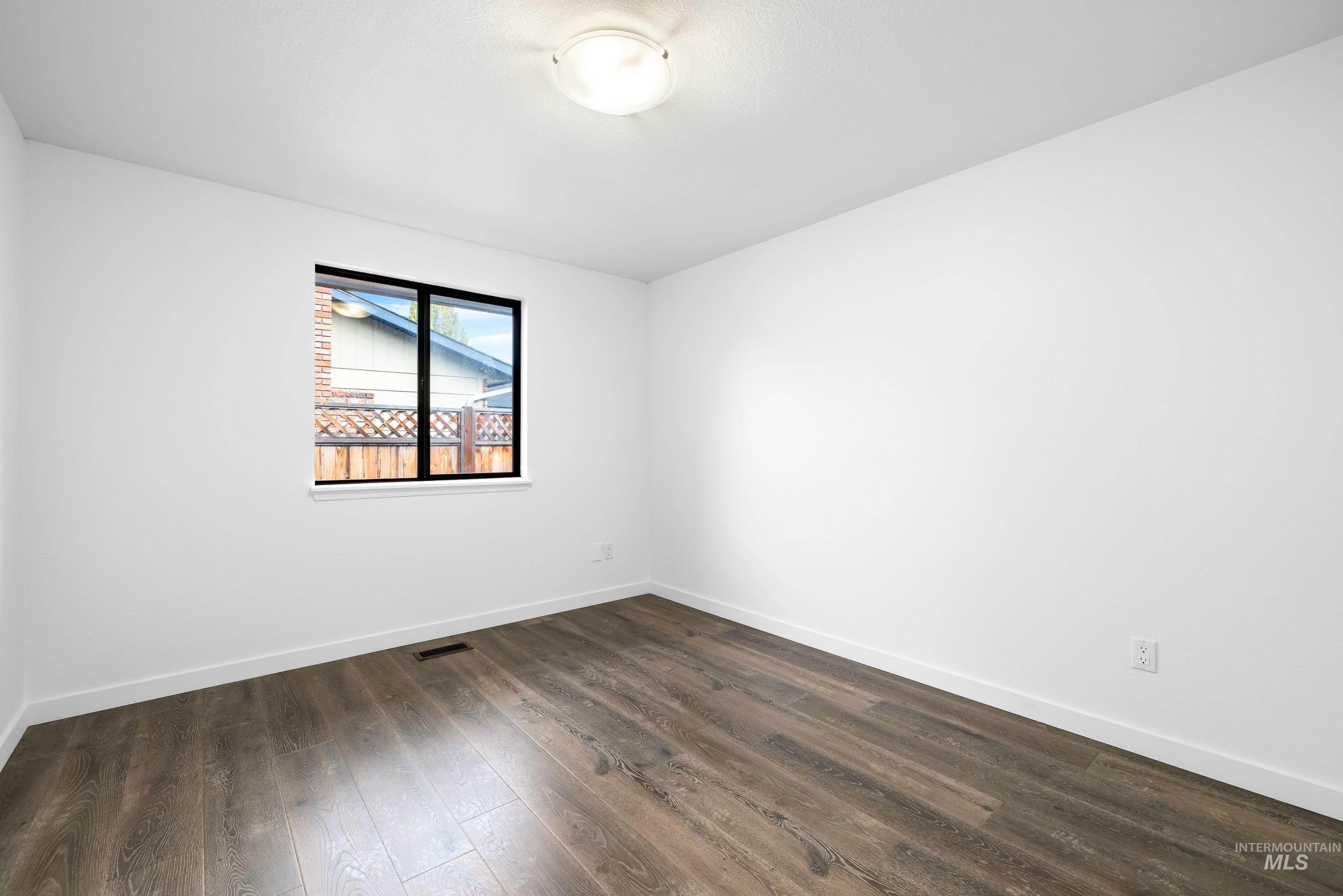 Empty room featuring dark wood-type flooring and baseboards