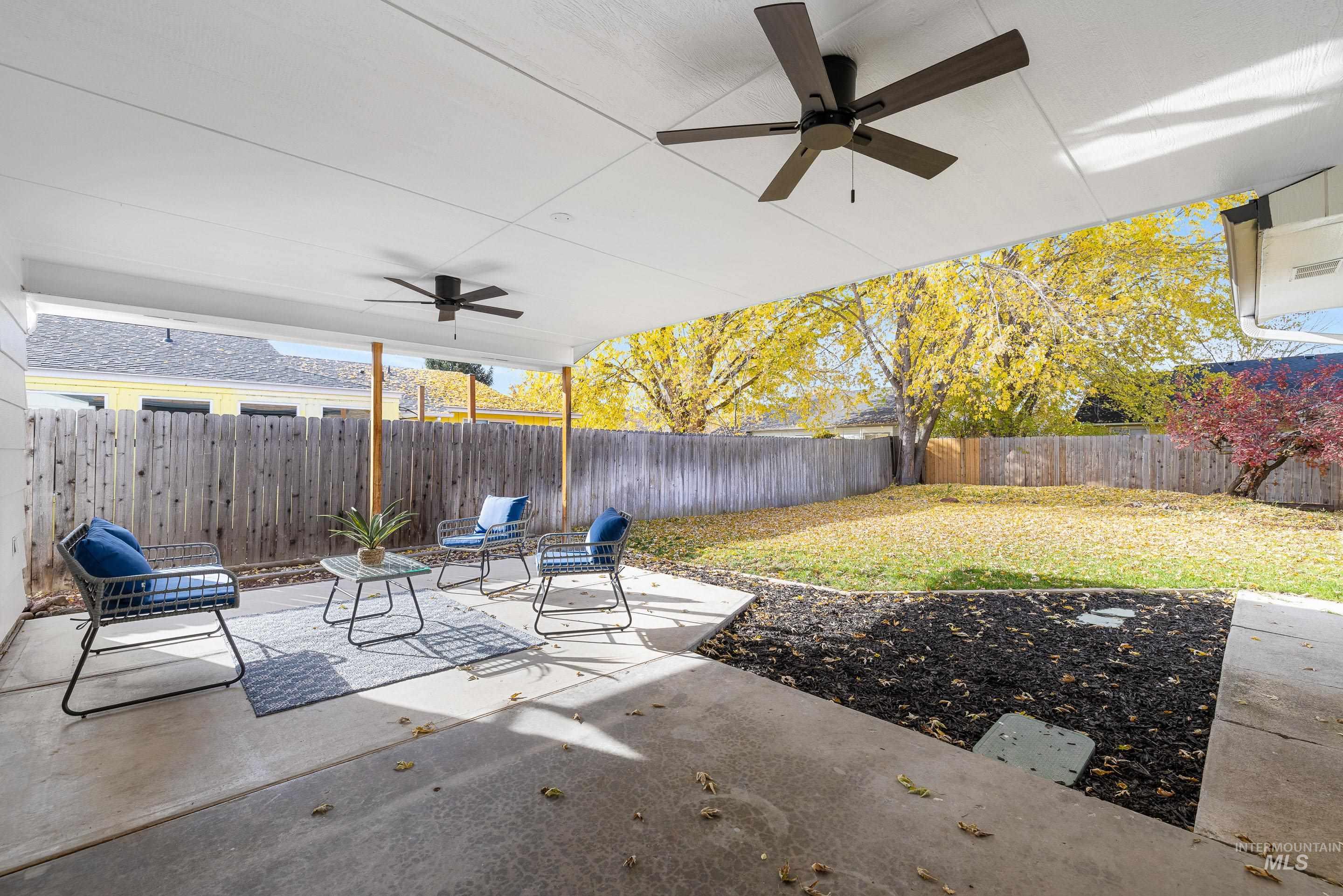 Fenced backyard featuring ceiling fan and a patio