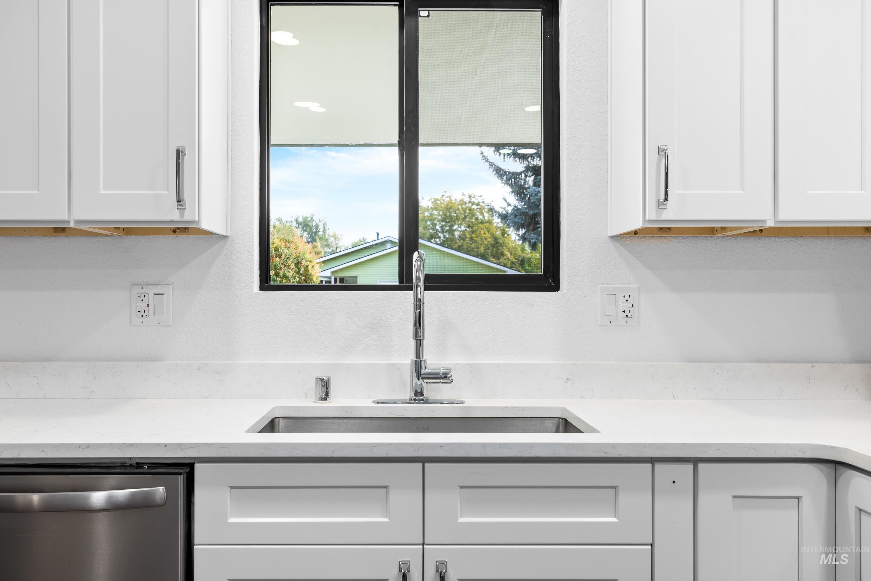 Kitchen featuring dishwasher, light stone counters, and white cabinets