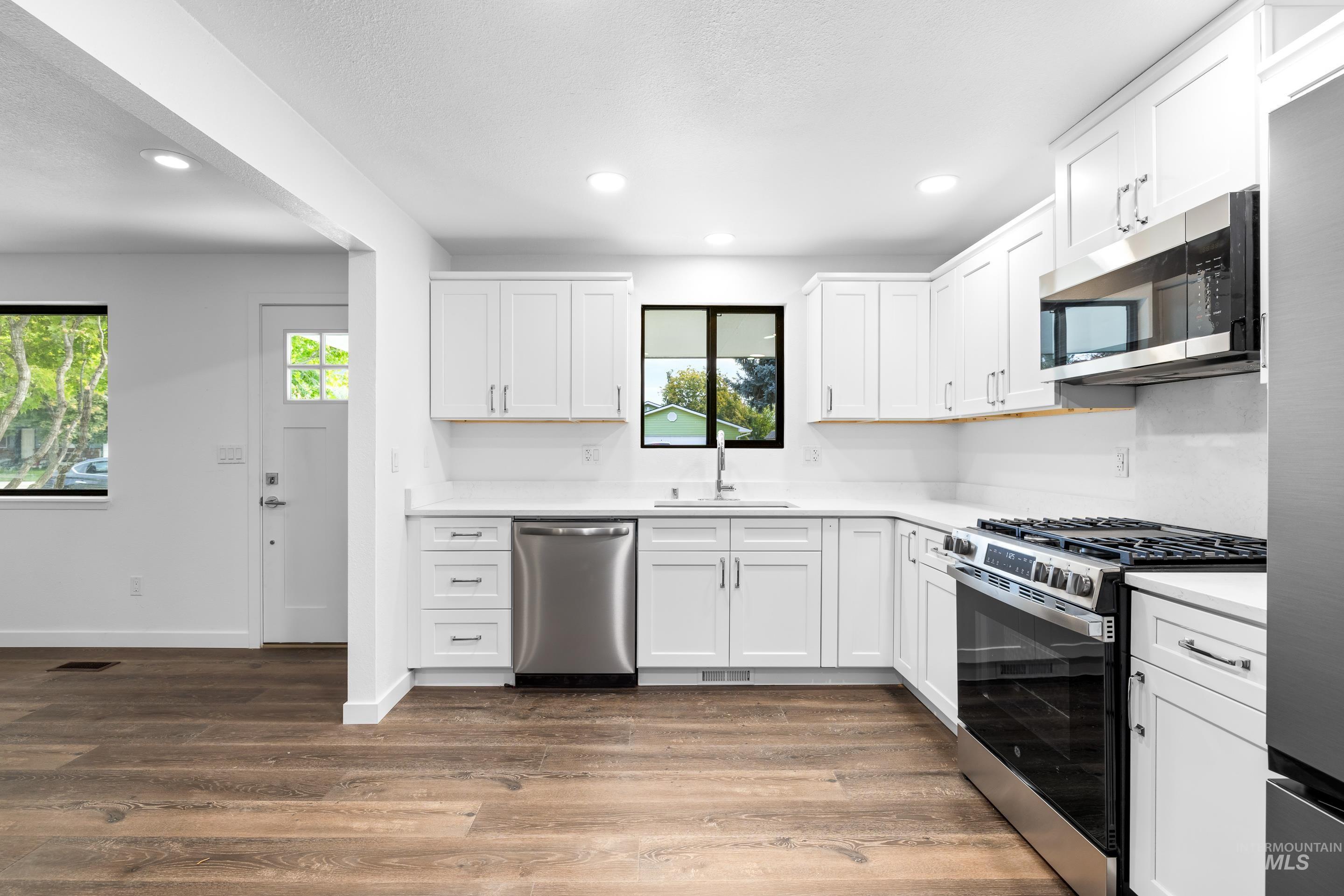 Kitchen featuring stainless steel appliances, white cabinets, dark wood finished floors, and recessed lighting