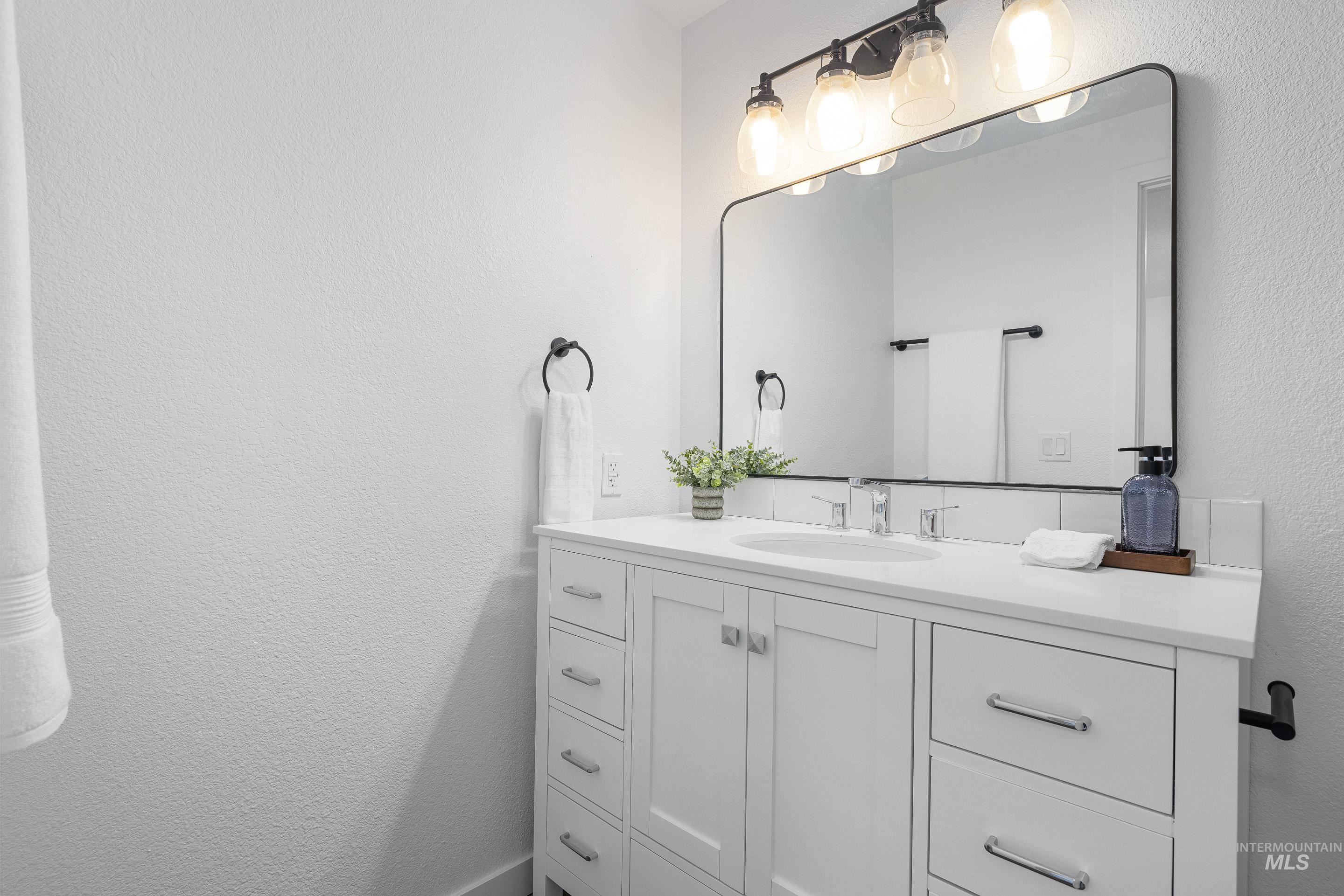 Bathroom featuring a textured wall and vanity