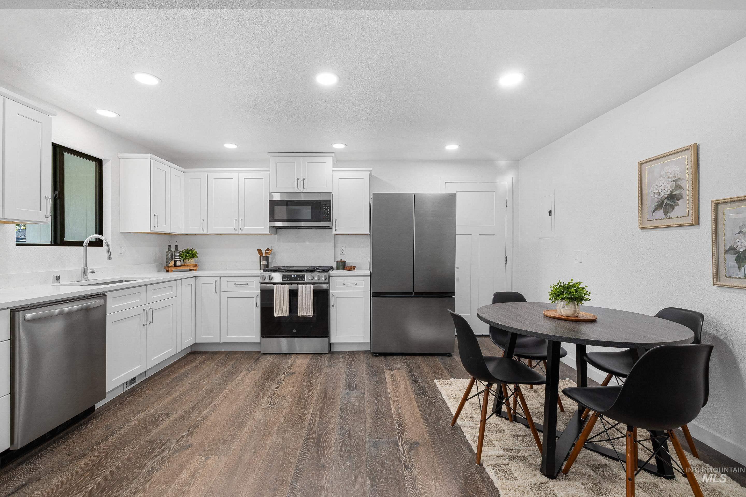 Kitchen with appliances with stainless steel finishes, white cabinets, dark wood-style floors, recessed lighting, and electric panel