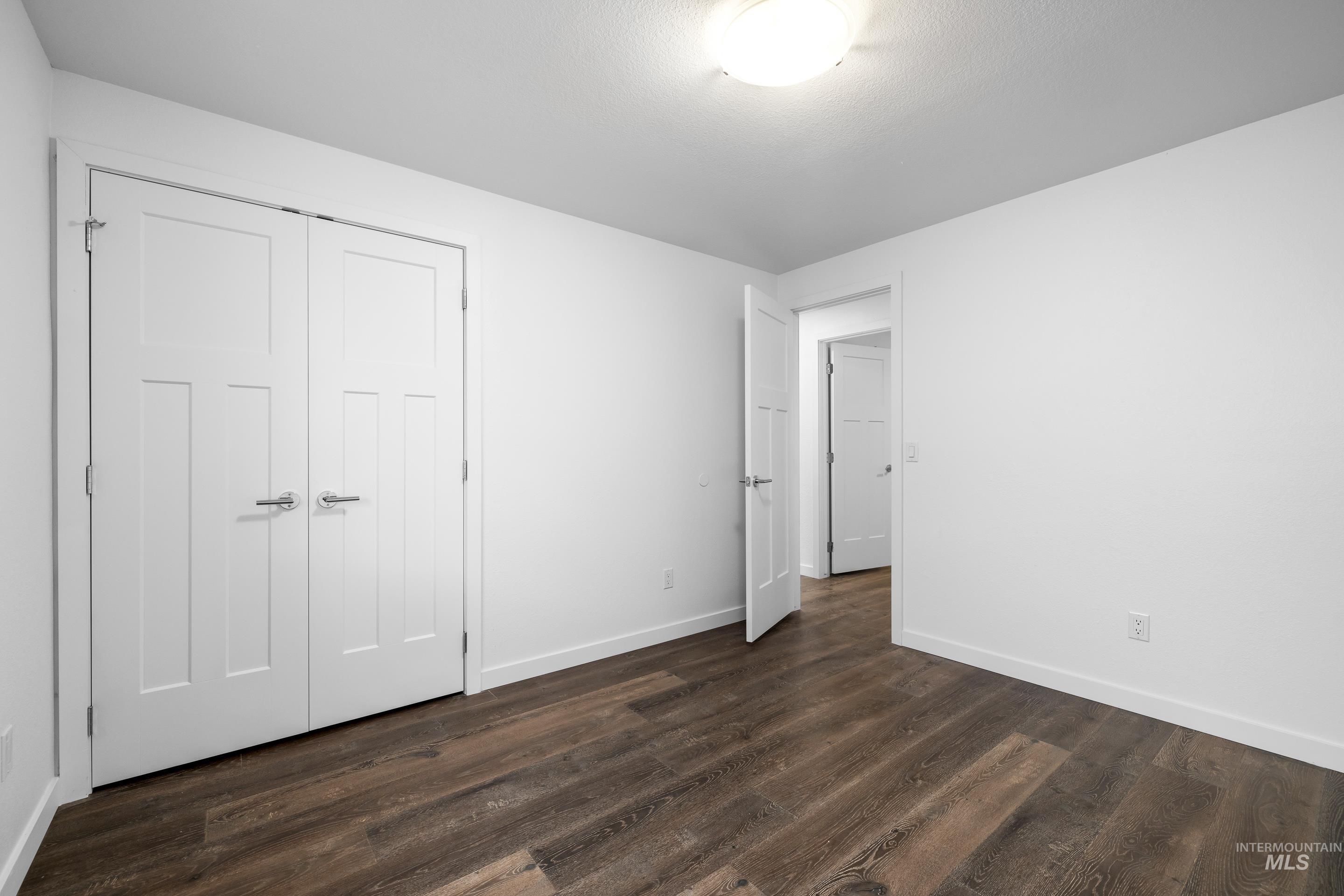 Unfurnished bedroom with dark wood-type flooring and a closet