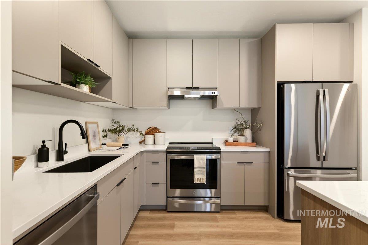 Kitchen with gray cabinets, stainless steel appliances, open shelves, and light wood-style floors