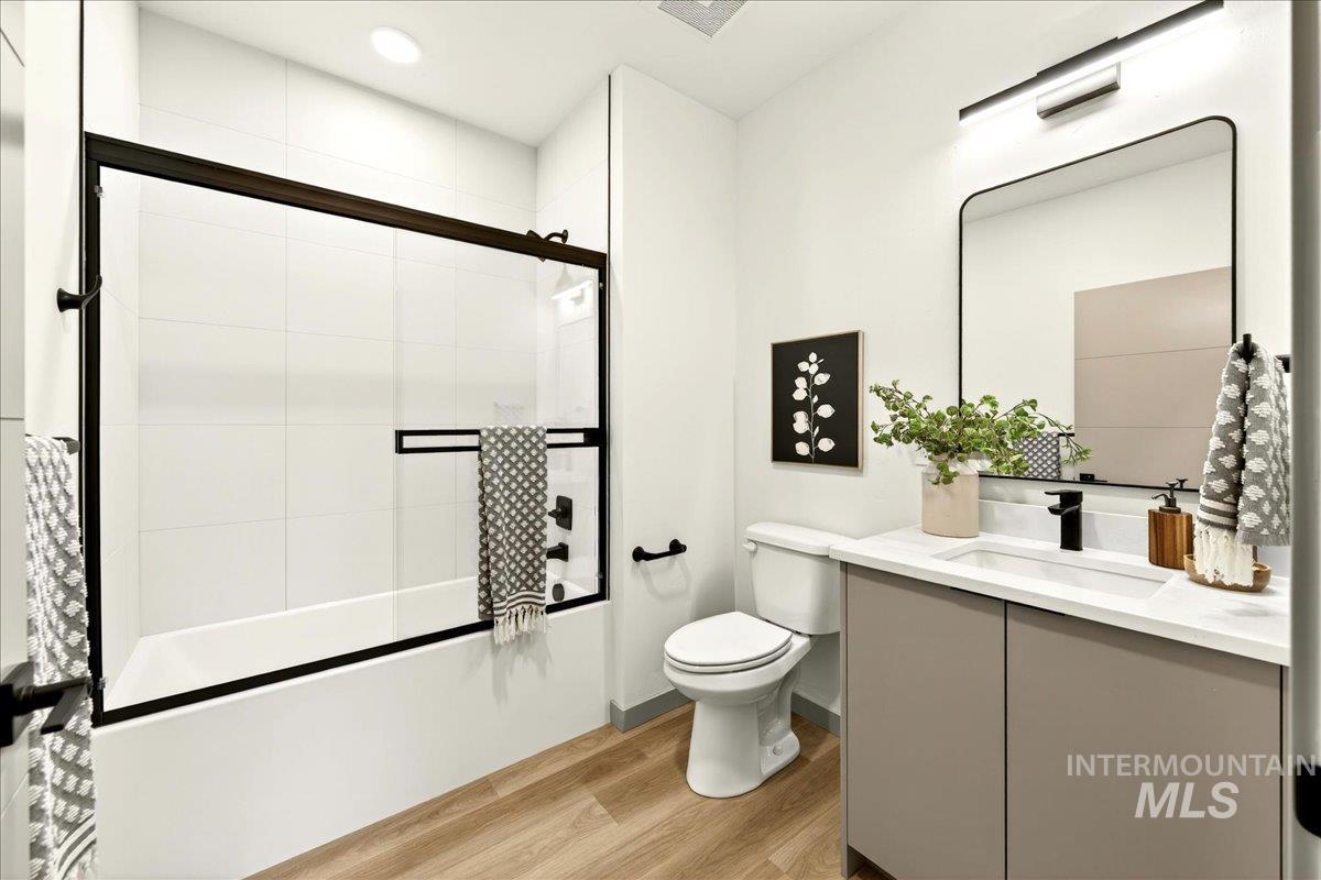 Bathroom with vanity, shower / bath combination with glass door, light wood finished floors, and recessed lighting
