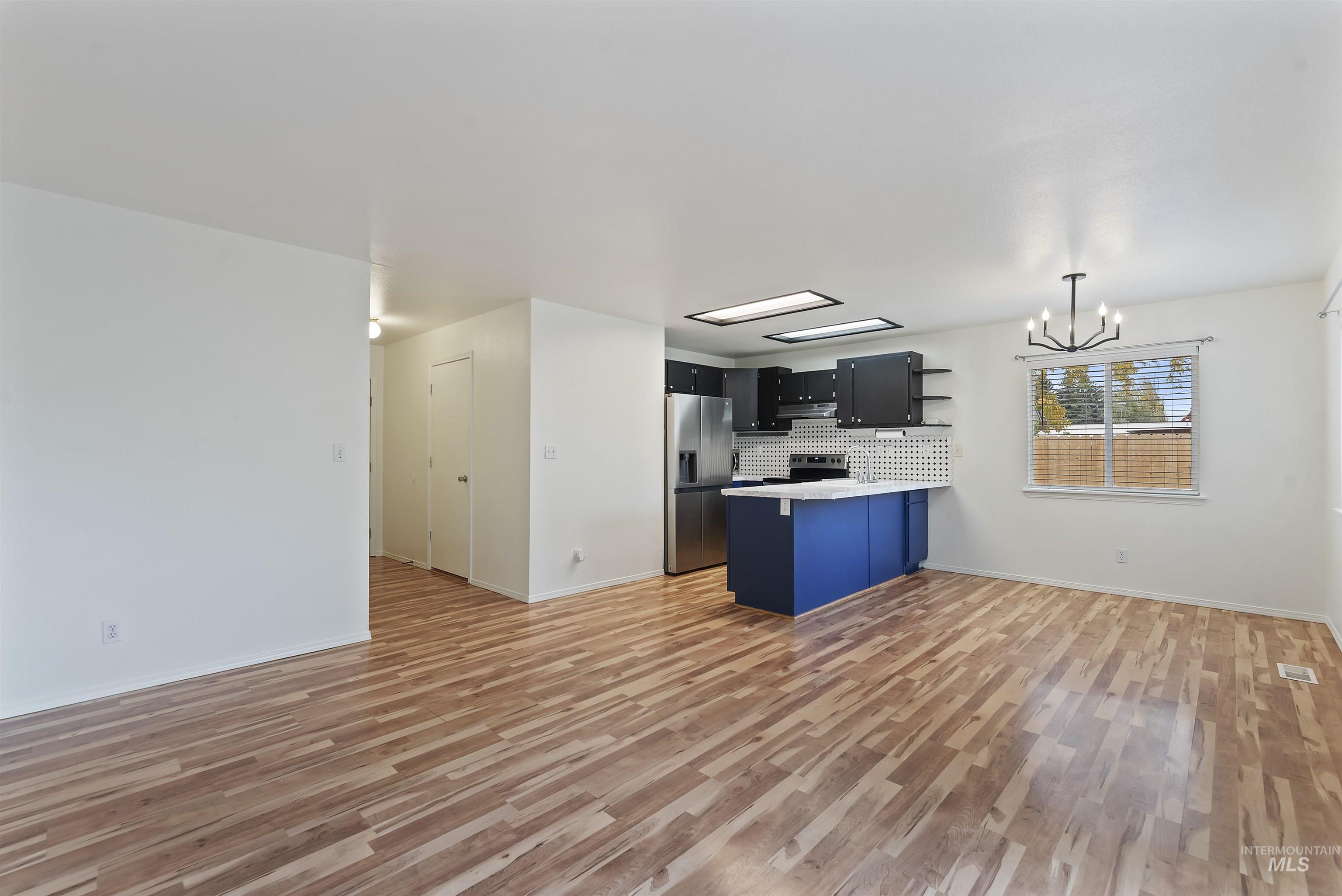 Kitchen featuring open floor plan, open shelves, light countertops, light wood-style floors, and a peninsula