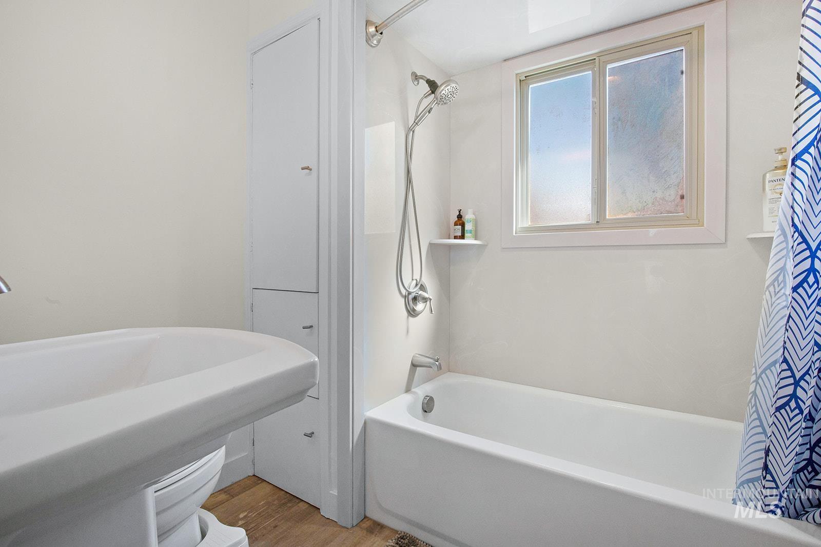 Full bathroom featuring shower / bath combo with shower curtain and light wood finished floors