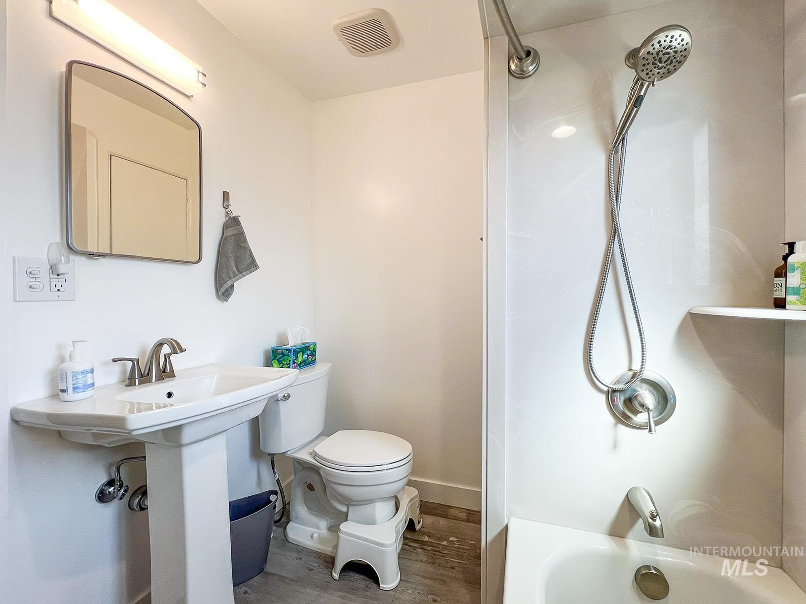 Full bath featuring wood finished floors and shower / bath combination