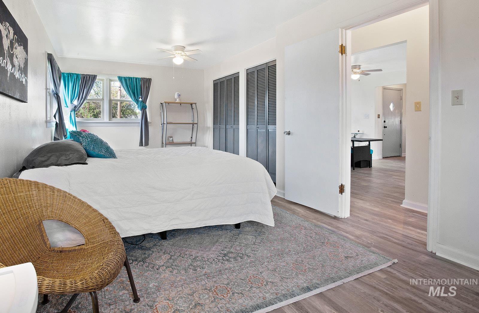 Bedroom featuring two closets, wood finished floors, and ceiling fan