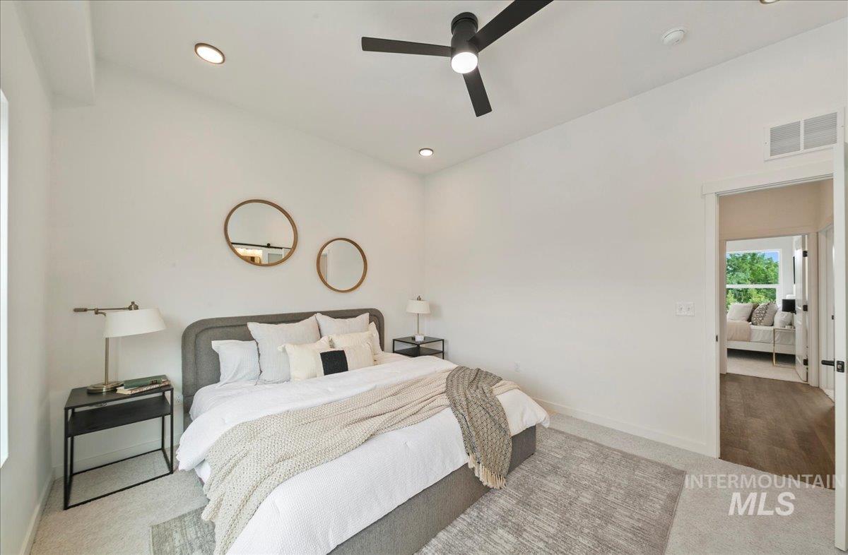Carpeted bedroom with a ceiling fan and recessed lighting