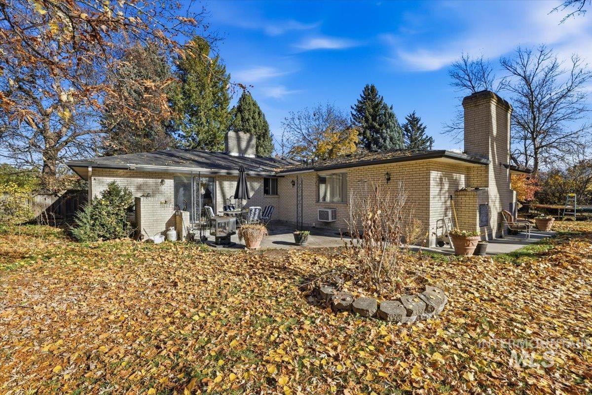 Rear view of property featuring a chimney, brick siding, and a patio area