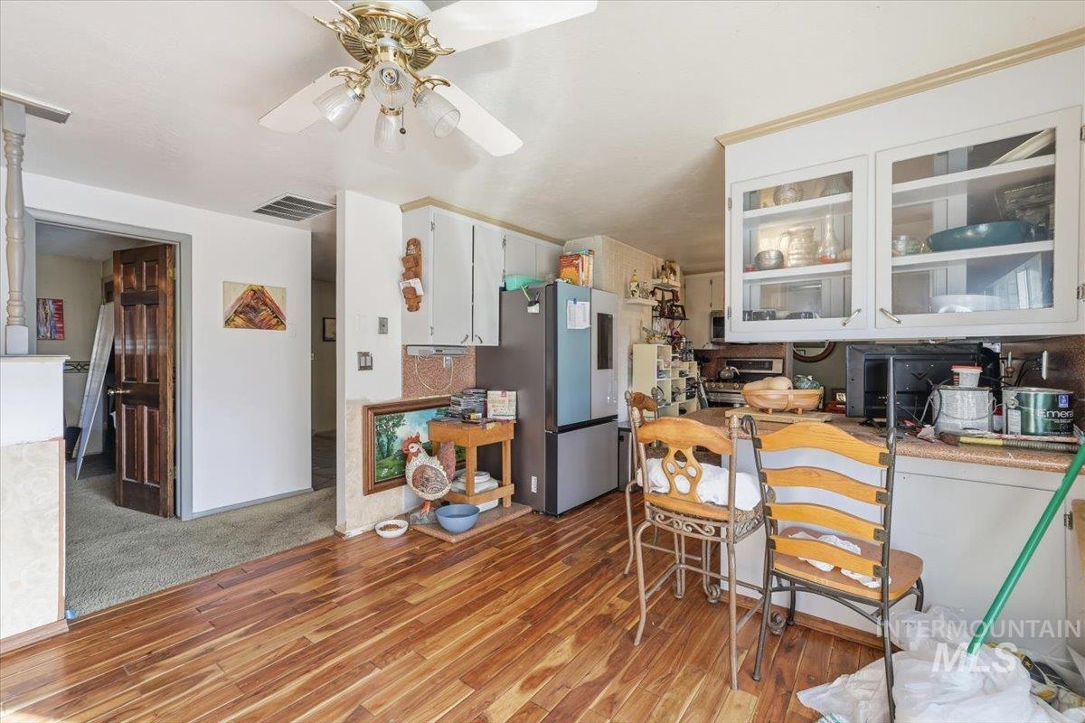 Kitchen with white cabinets, appliances with stainless steel finishes, glass insert cabinets, light wood finished floors, and light countertops