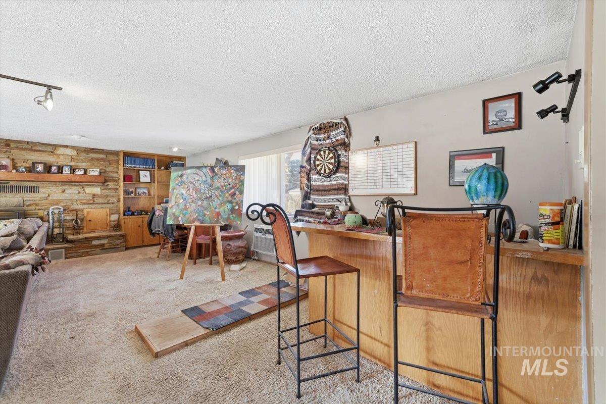 Bar area featuring a textured ceiling, light carpet, and an AC wall unit