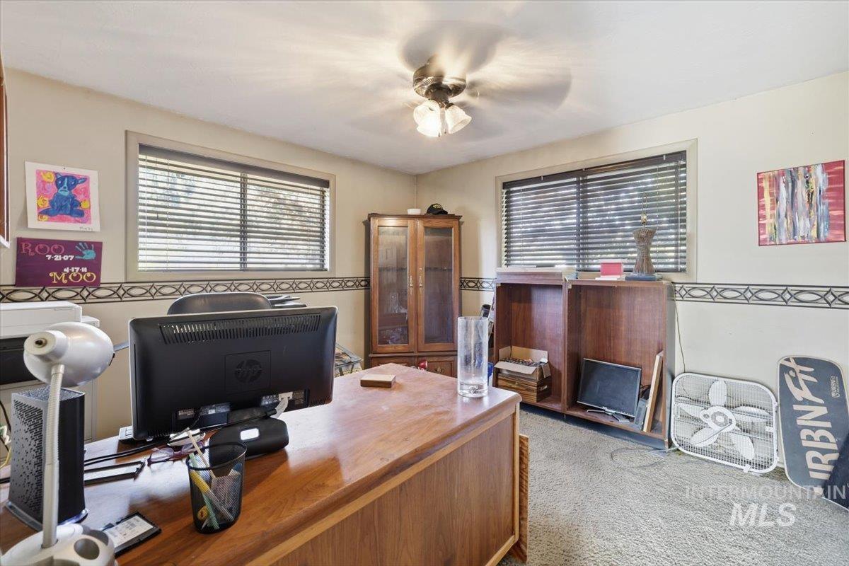 Home office with light colored carpet and a ceiling fan
