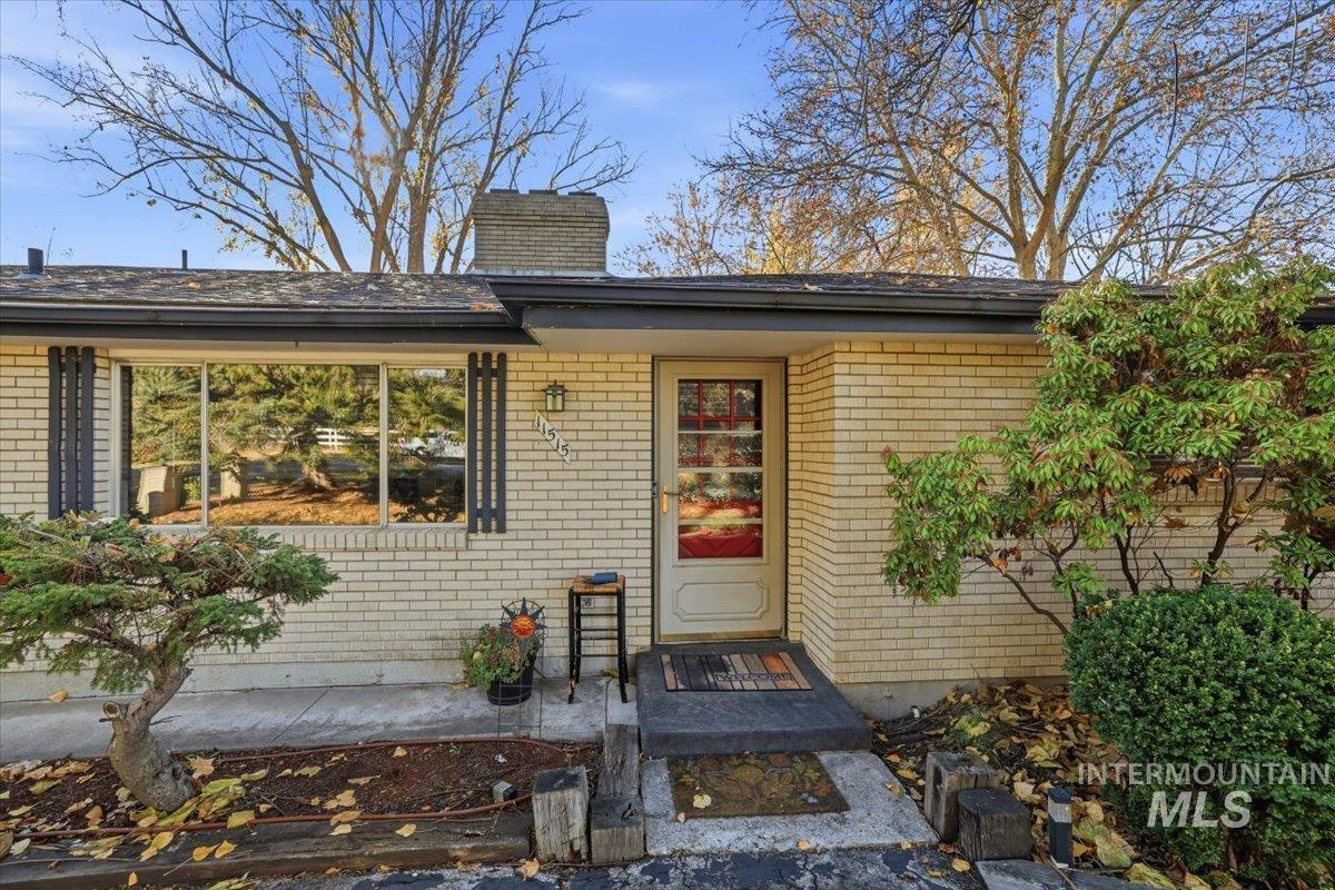 Doorway to property with a chimney and brick siding
